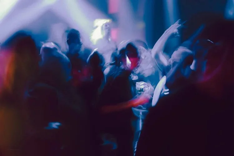 People dancing and enjoying music at a nightclub with colorful lights.