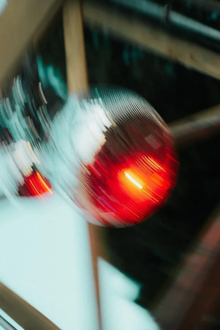 Blurry photo of a red and orange traffic light seen from the side, with parts of a stove and kitchen counter visible in the background.