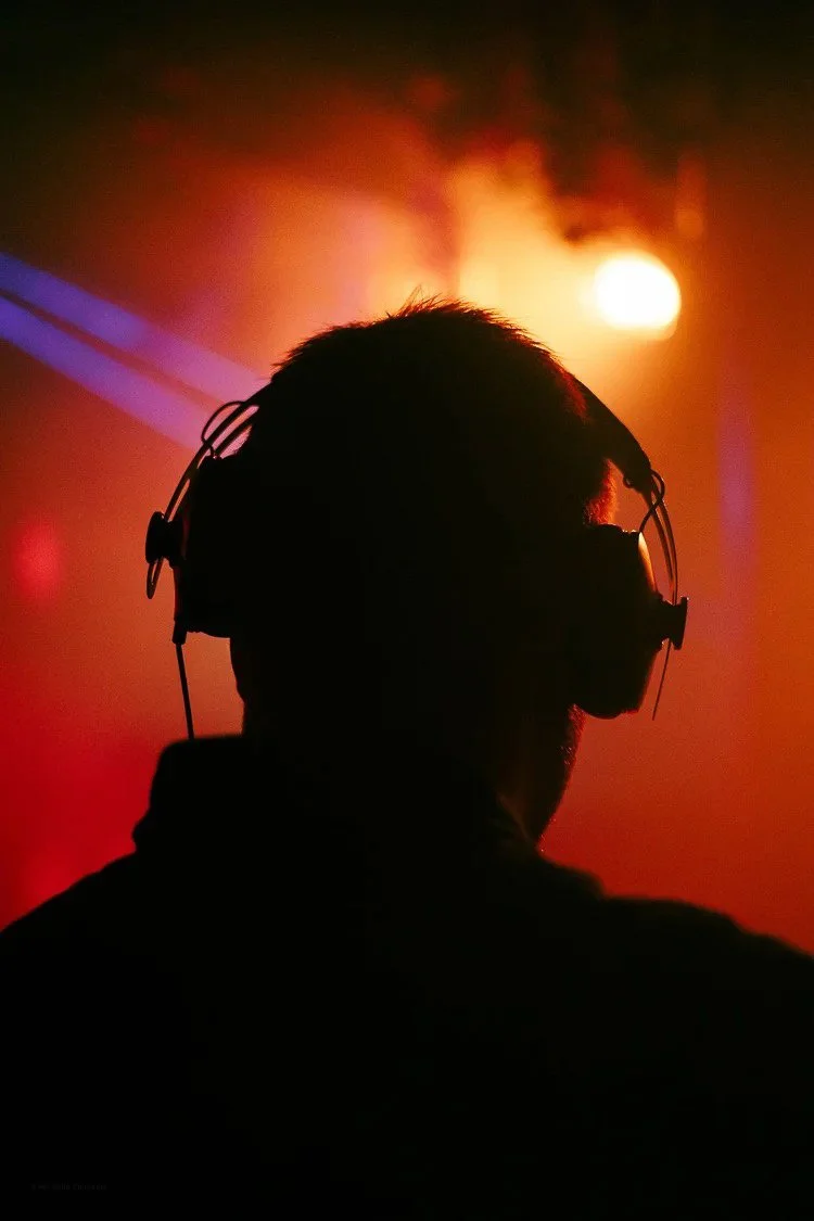 Silhouette of a person wearing headphones with a red and orange sunset background.