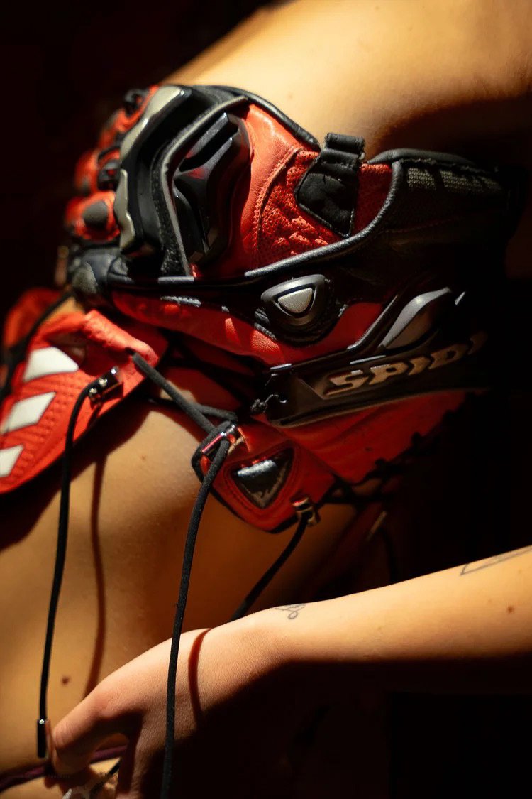 Close-up of a red and black racing glove resting on a person's leg.