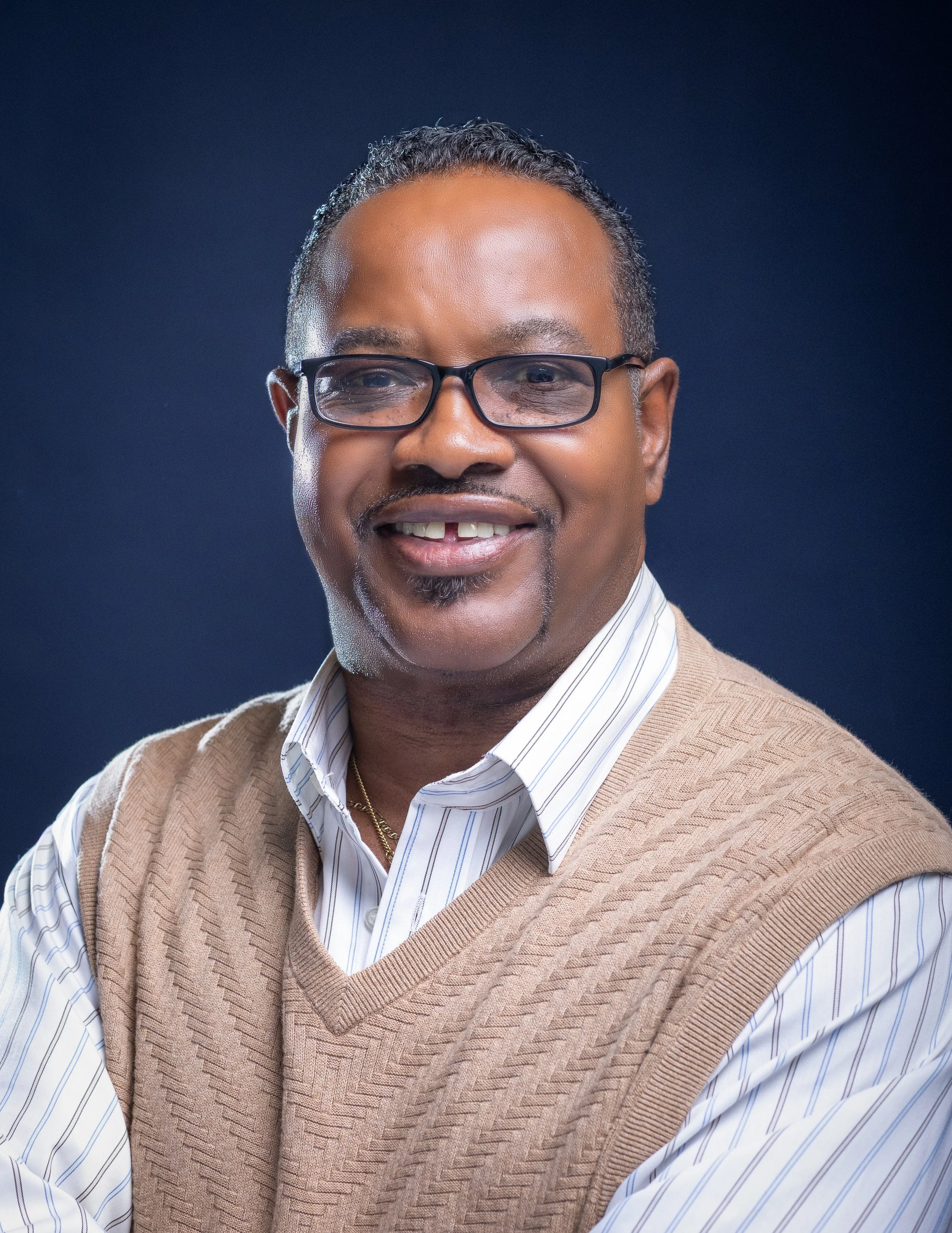 Close-up headshot of Anthony Poplar, Property Manager at NACD, smiling warmly, against a warm grey background.