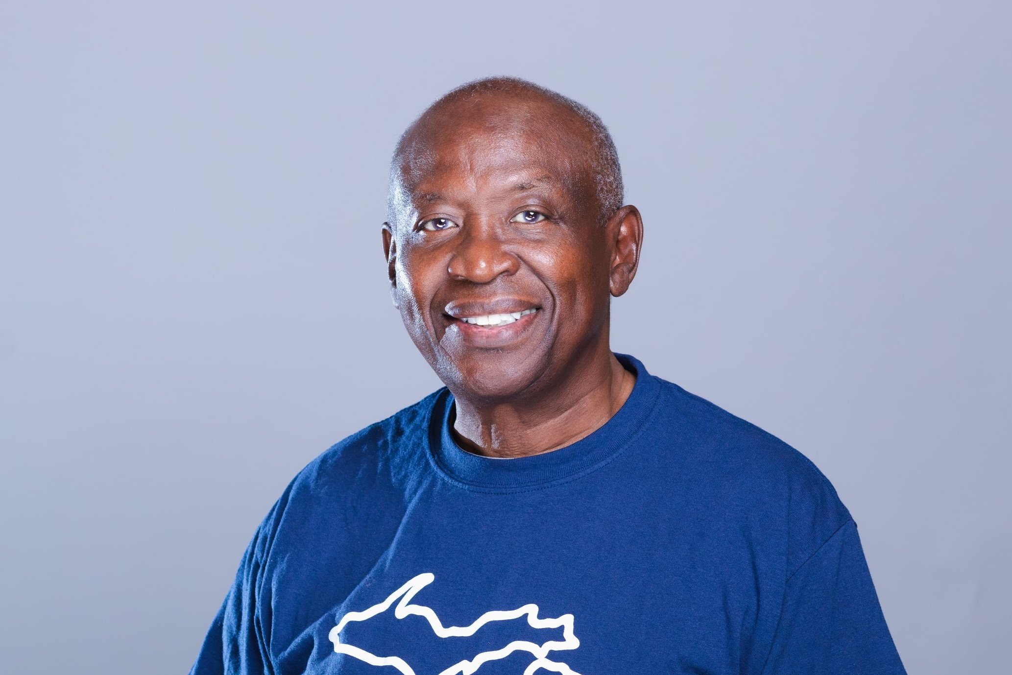 Close-up headshot of Charles Willis, Treasurer of the NACD Board of Directors, smiling warmly, against a warm grey background.