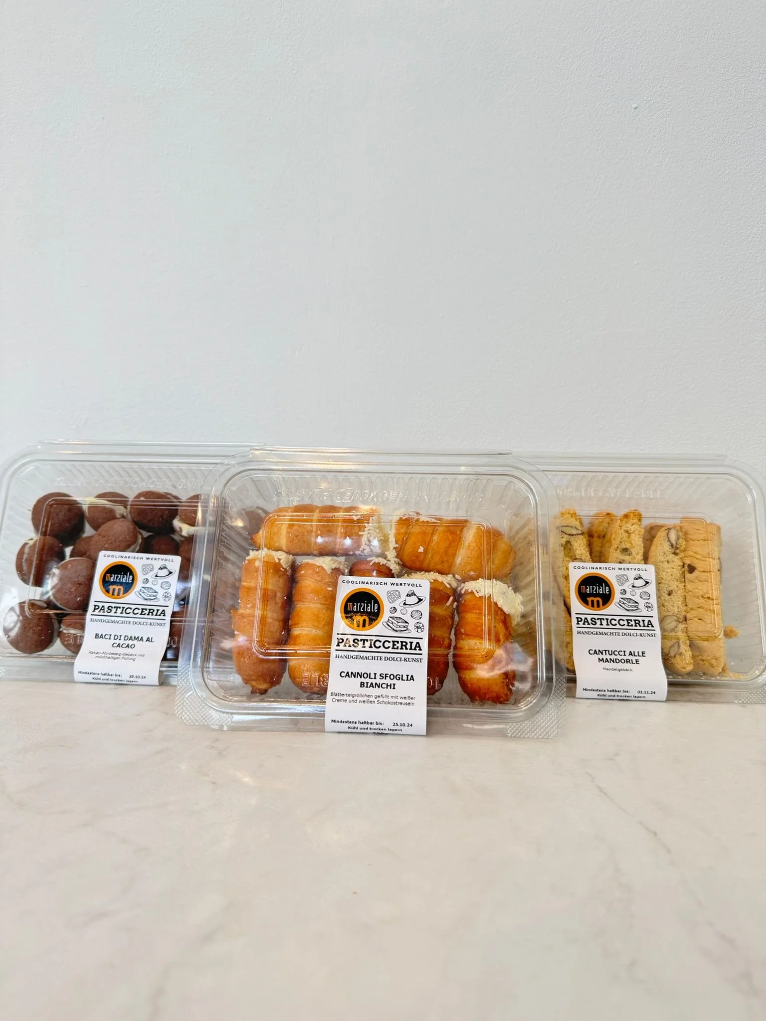 Drei Sorten orientalischer Süßgebäck-Mix in transparenter Verpackung: Dattelkonfekt, Pistazienrollen und Mandelgebäck - perfekt für To-go oder Mitbringsel.Ob belegte Croissants oder einfach nur becher stuttgart, alles an einem Ort in deiner nähe.