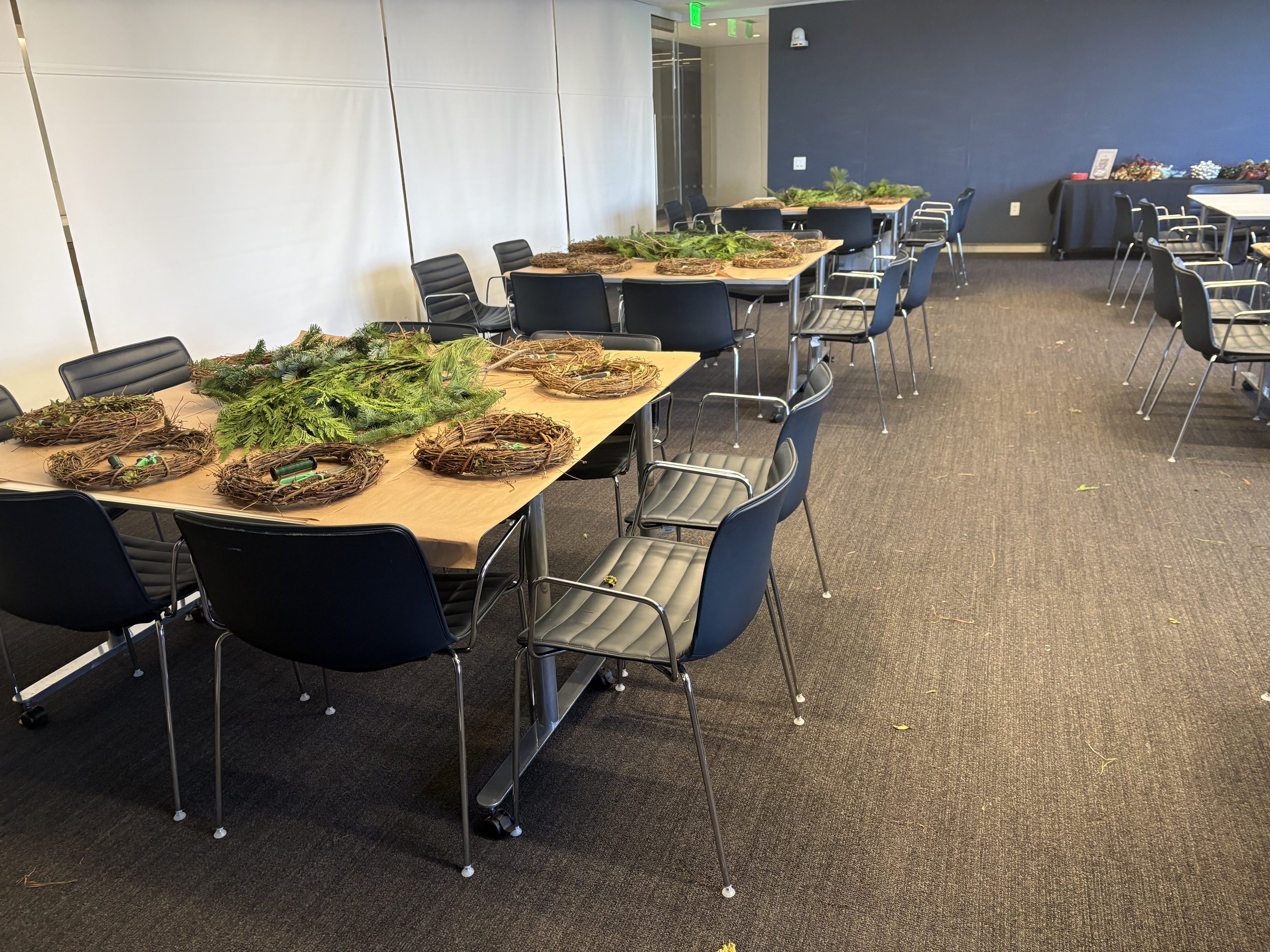 Empty conference room with tables decorated with holiday greenery and wreaths, and chairs around the tables.