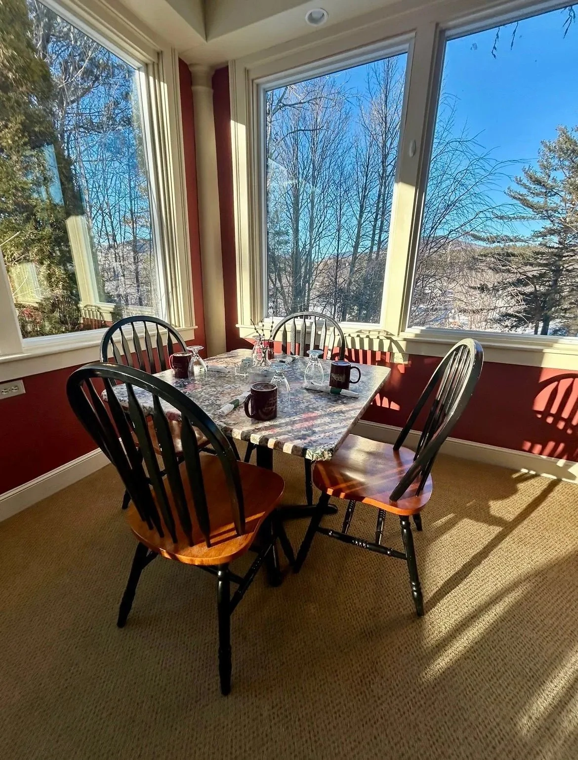 A breakfast table at the "Inn at Jackson" in Jackson, New Hampshire, situated next to large windows showing a winter landscape with leafless trees and blue sky.