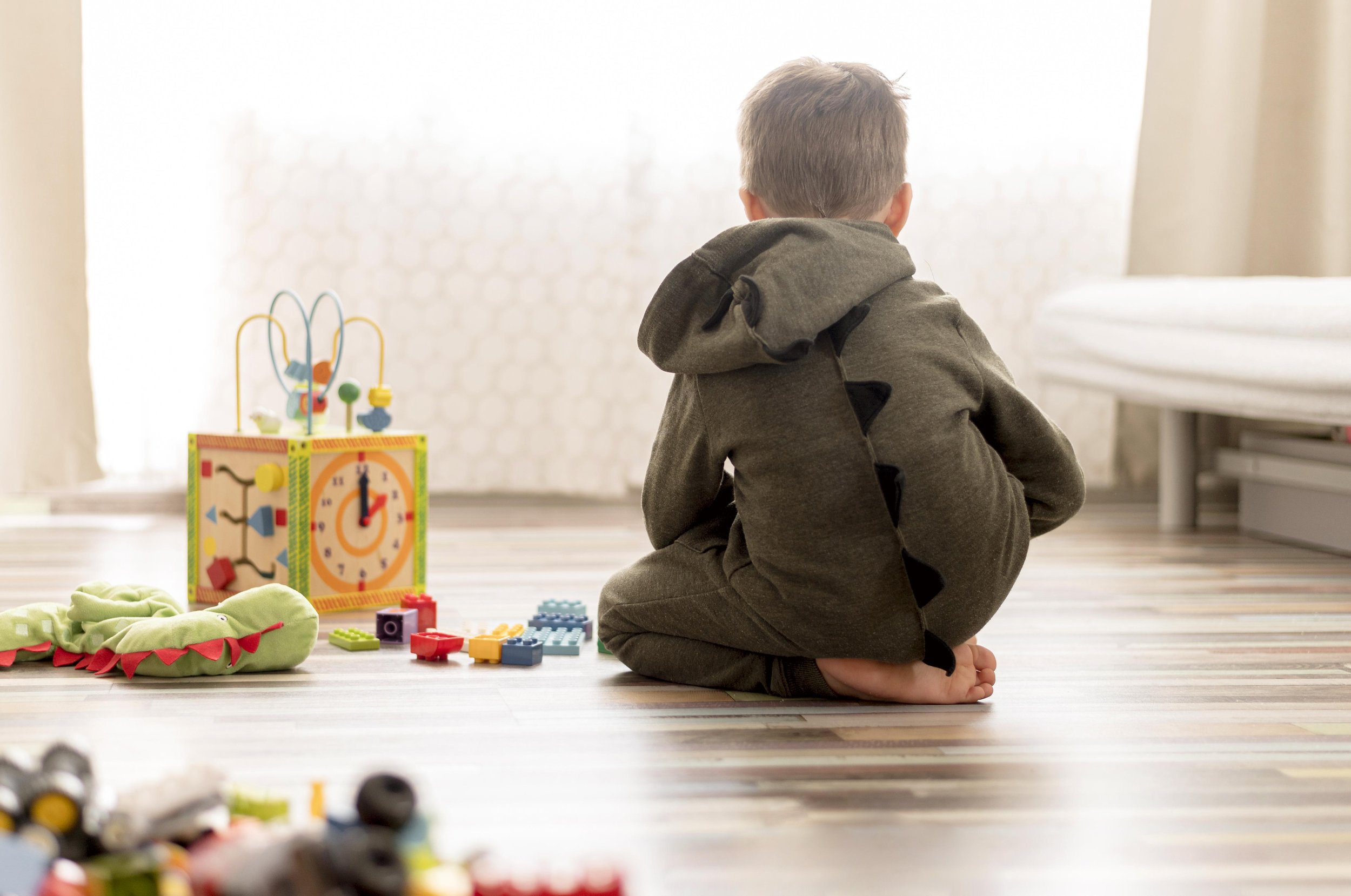 Little boy in a dino costume playing in the floor.