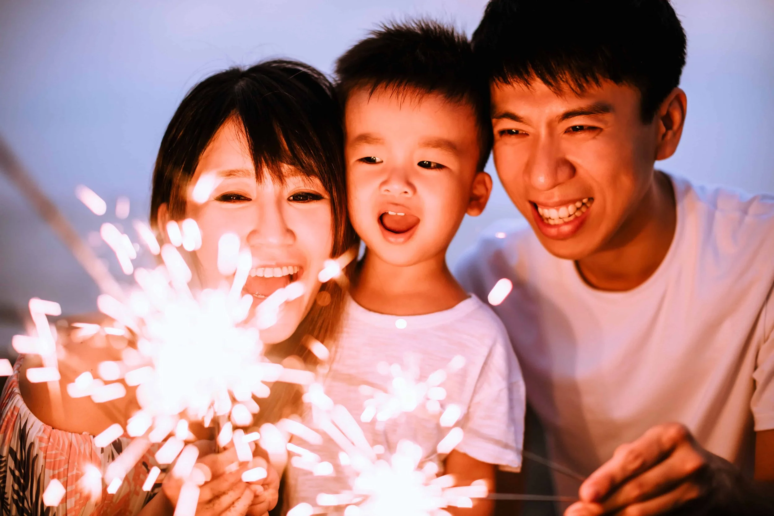 Asian parents and small son enjoing a sparkler
