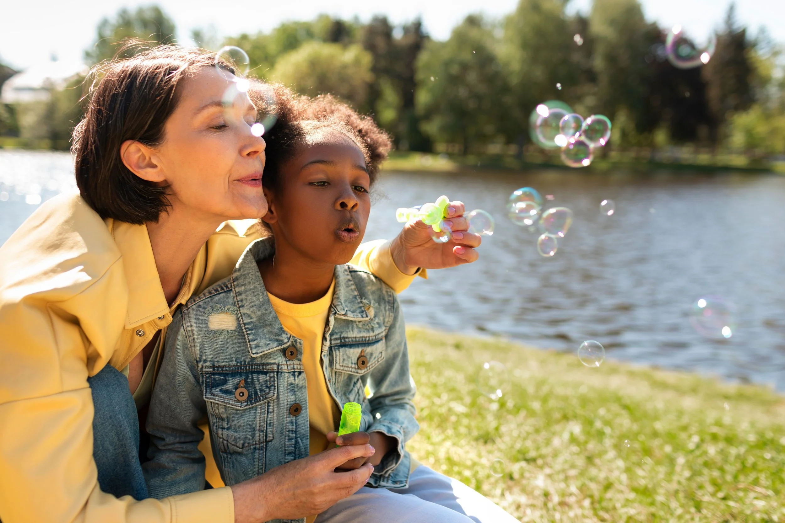 Nanny blowing bubbles with little girl at the park