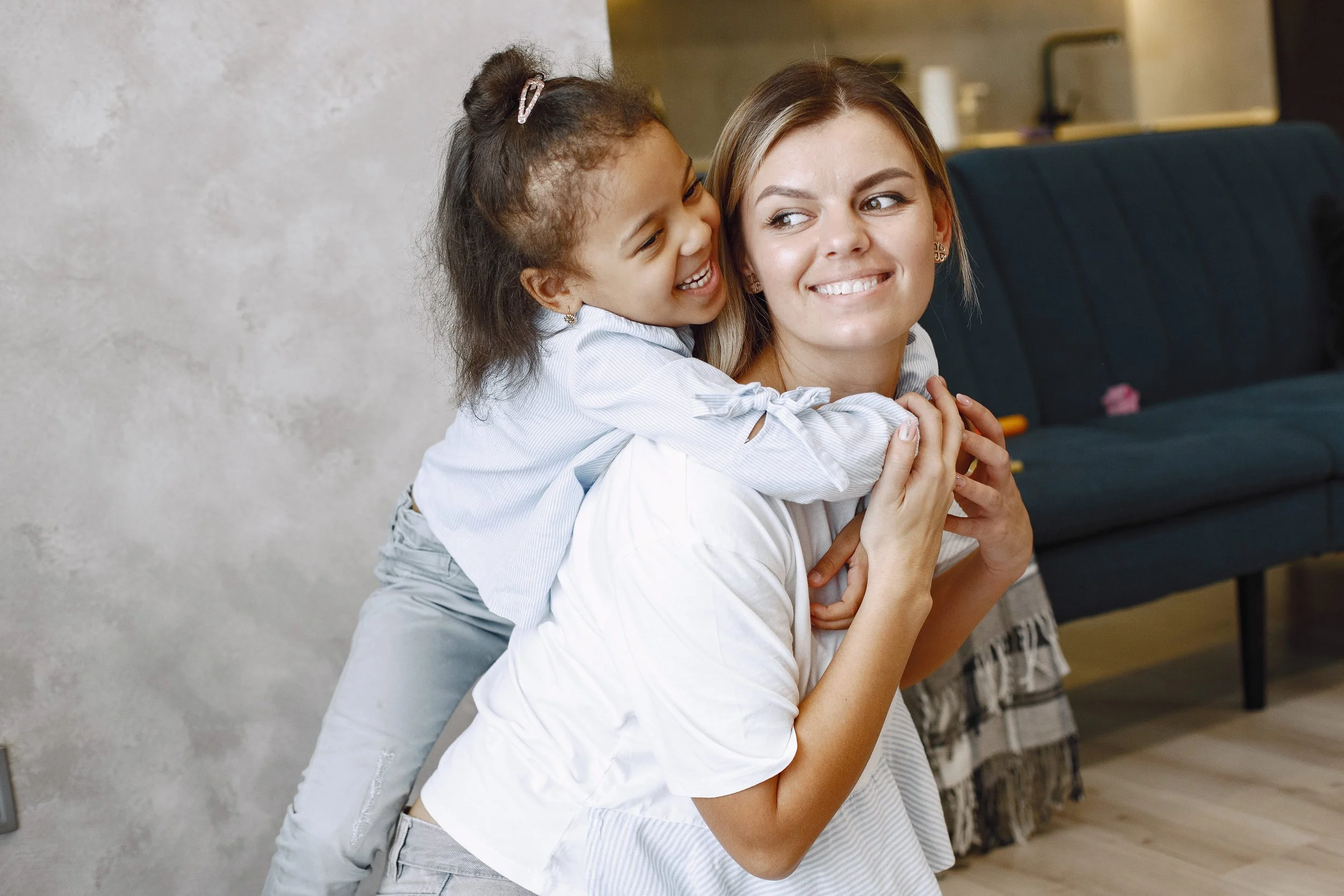 Little girl laughing and climbing on babysitter's shoulders.