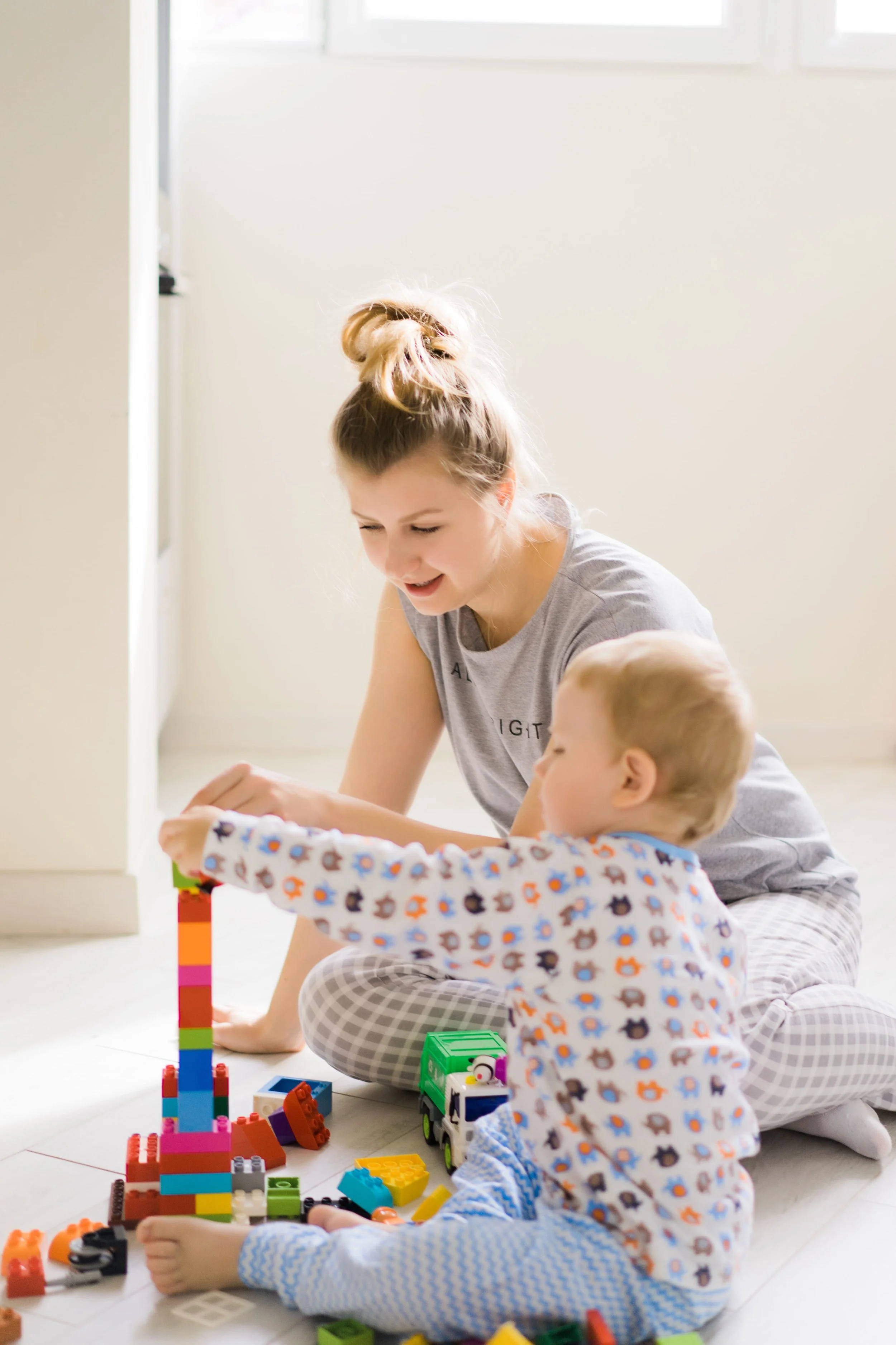 Nanny playing blocks with little boy on the floor