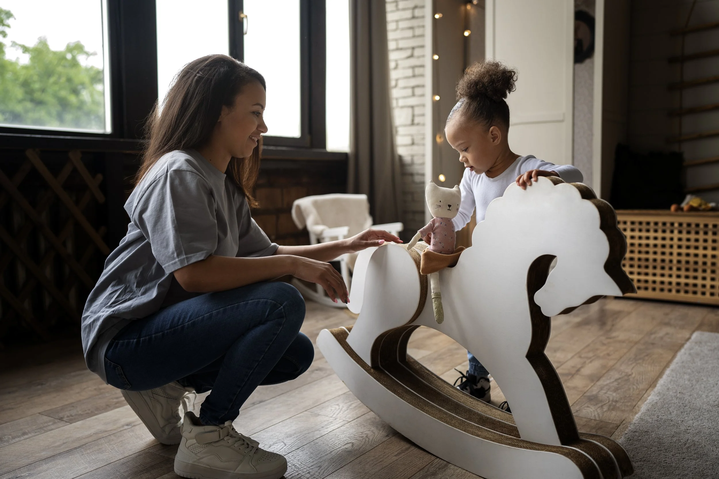 Babysitter helping little girl get on a hobby horse