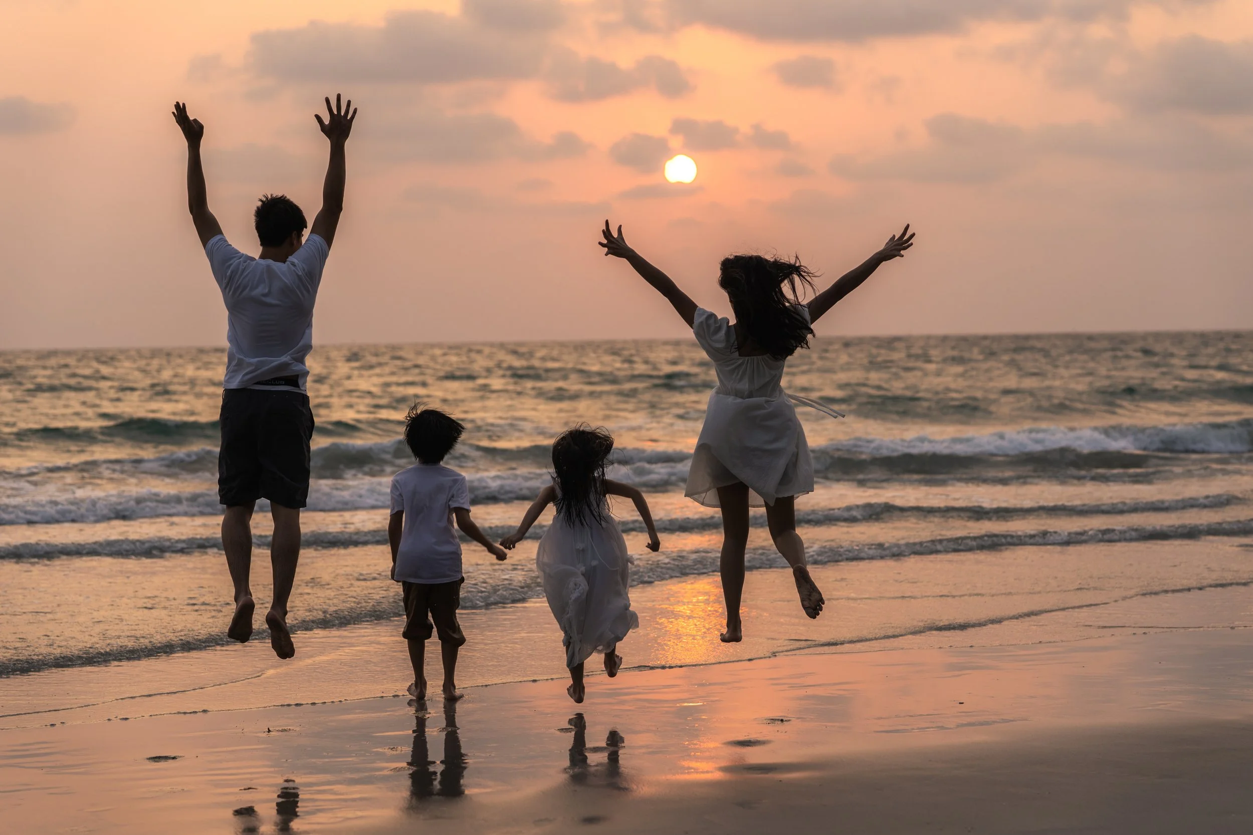 Family walking together on the beach at sunset