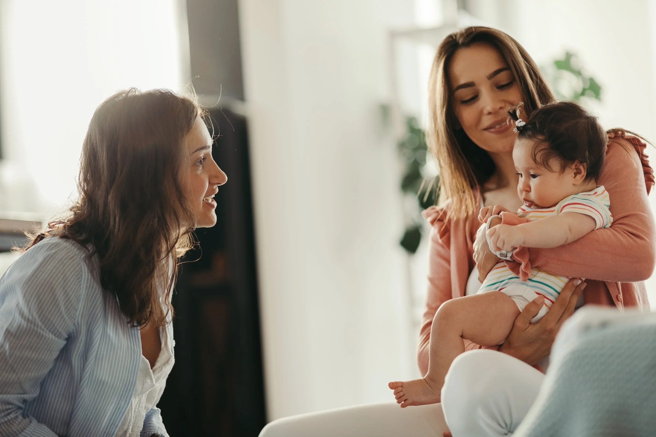 Mom talking with babysitter with baby in her lap