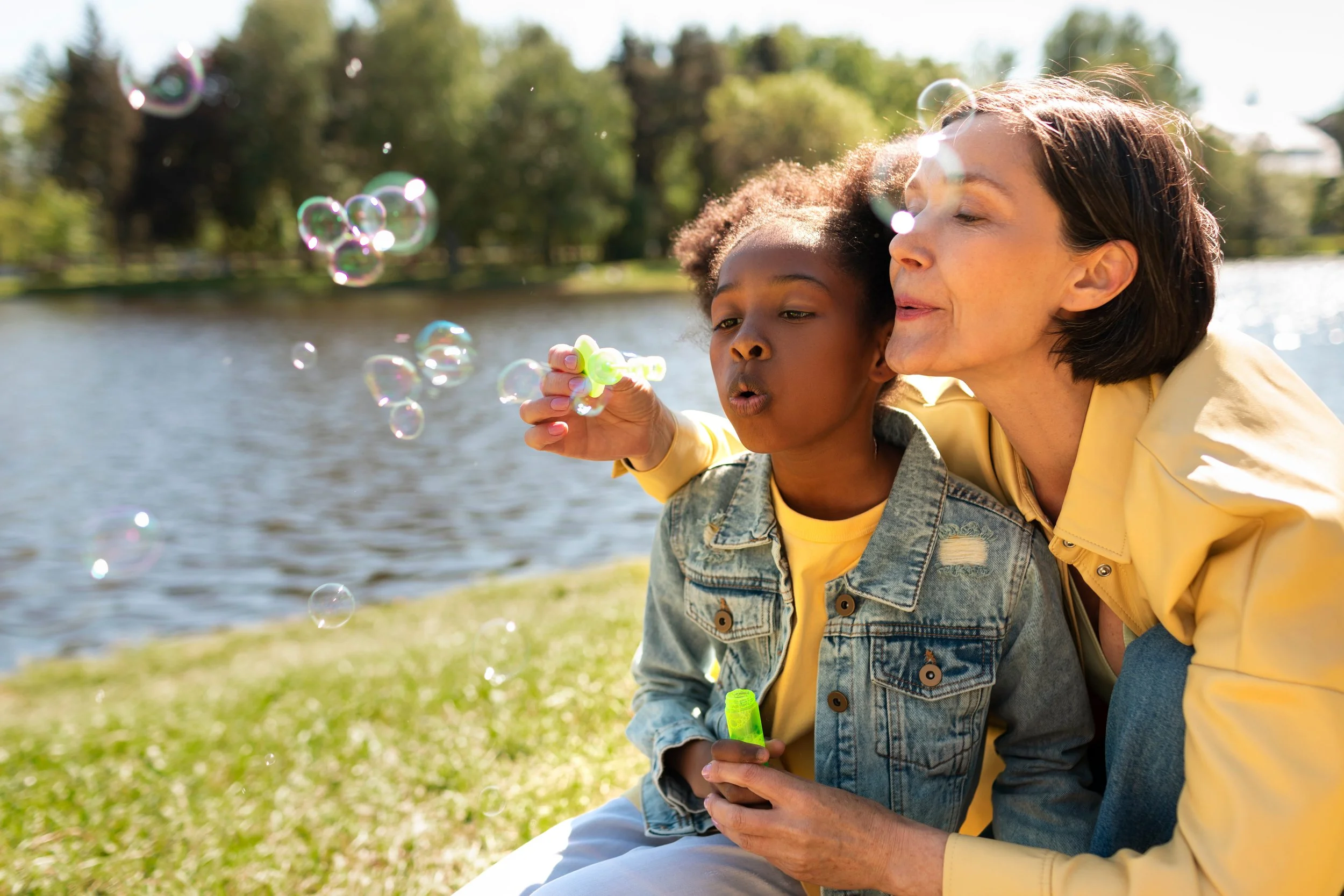 Nanny and little girl playing with bubbles outside
