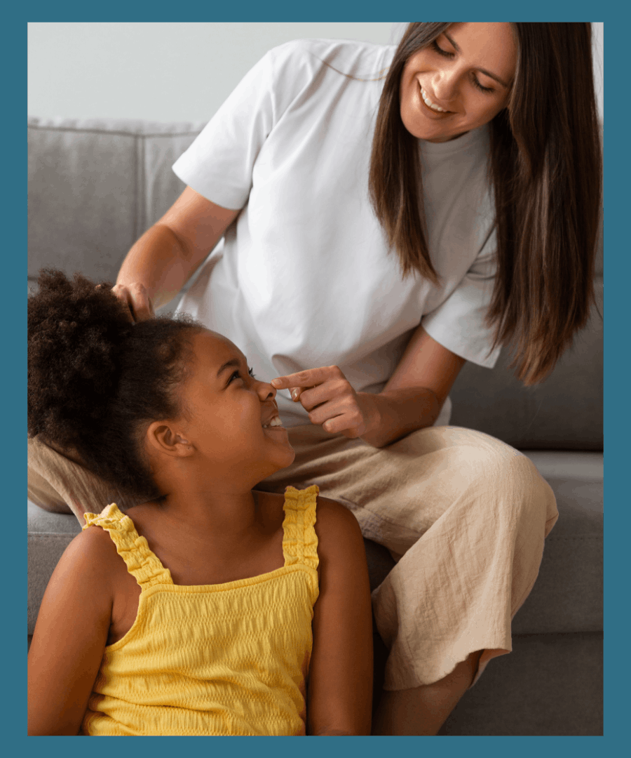 Babysitter and little girl are laughing as the sitter is doing the girl's hair.