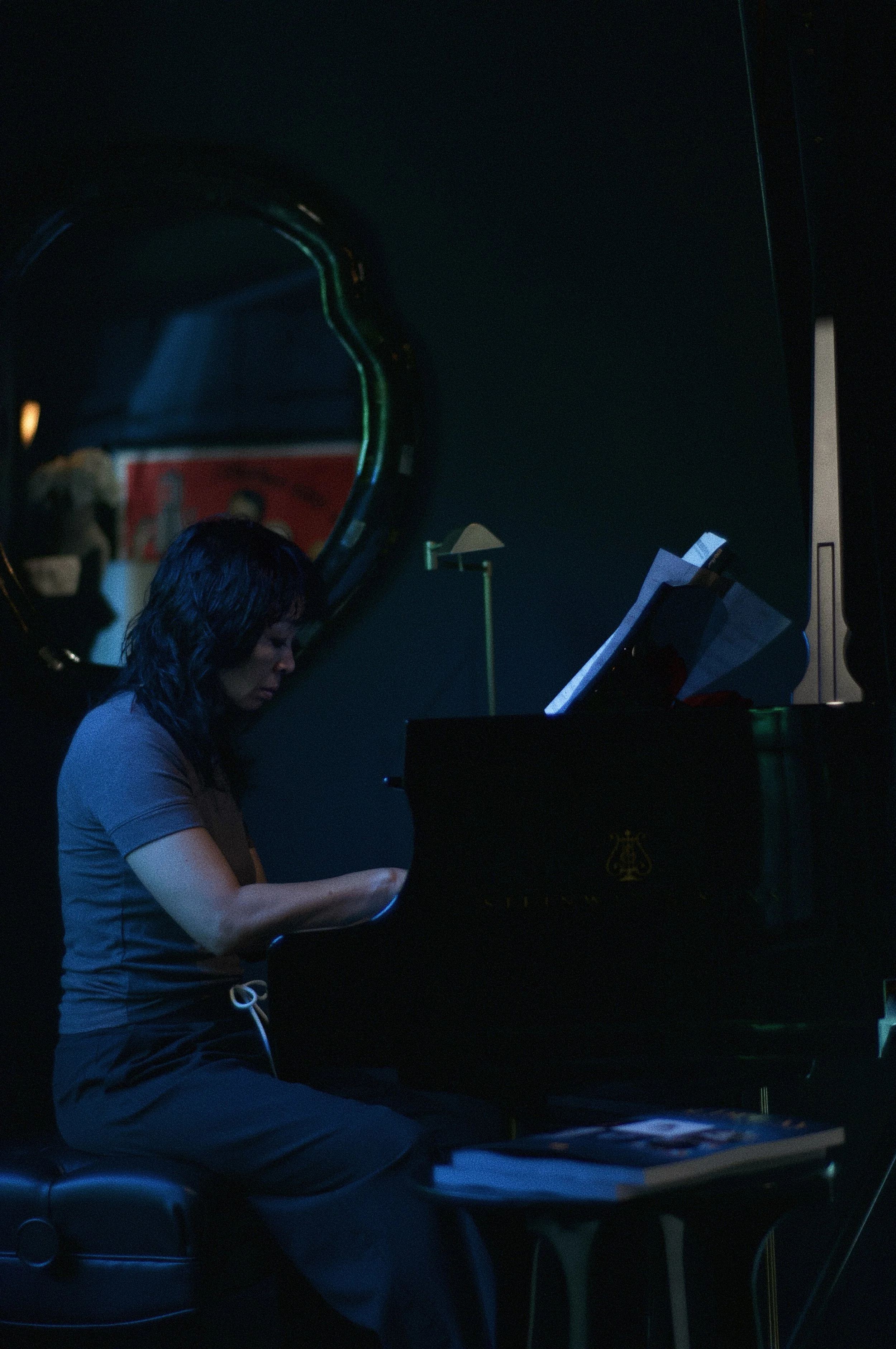 Victoria Maison seated at a grand piano in her music room, looking down at the keys.
