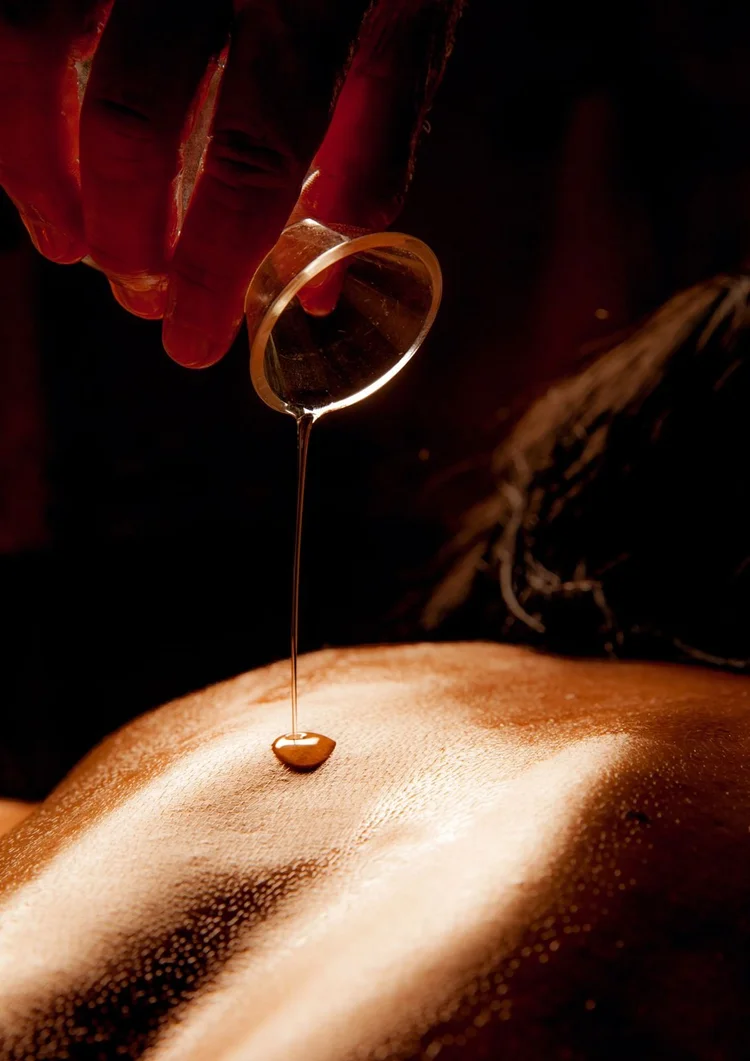 Warm aromatic oil dripping onto the back before a massage