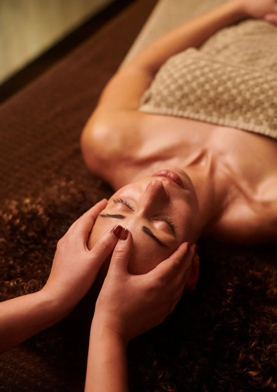 Relaxing facial massage, therapist’s hands resting at the temples