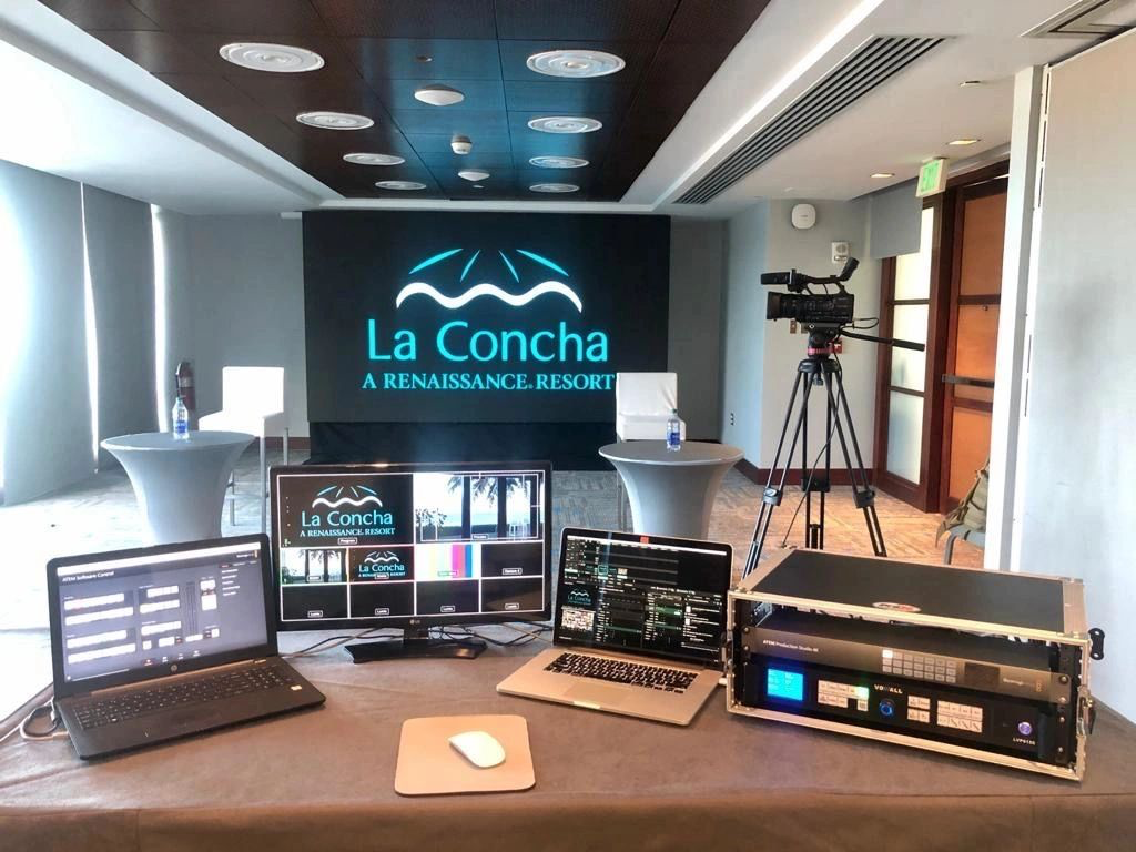 Conference room setup with AV equipment, laptops, video camera, and screen displaying "La Concha A Renaissance Resort."