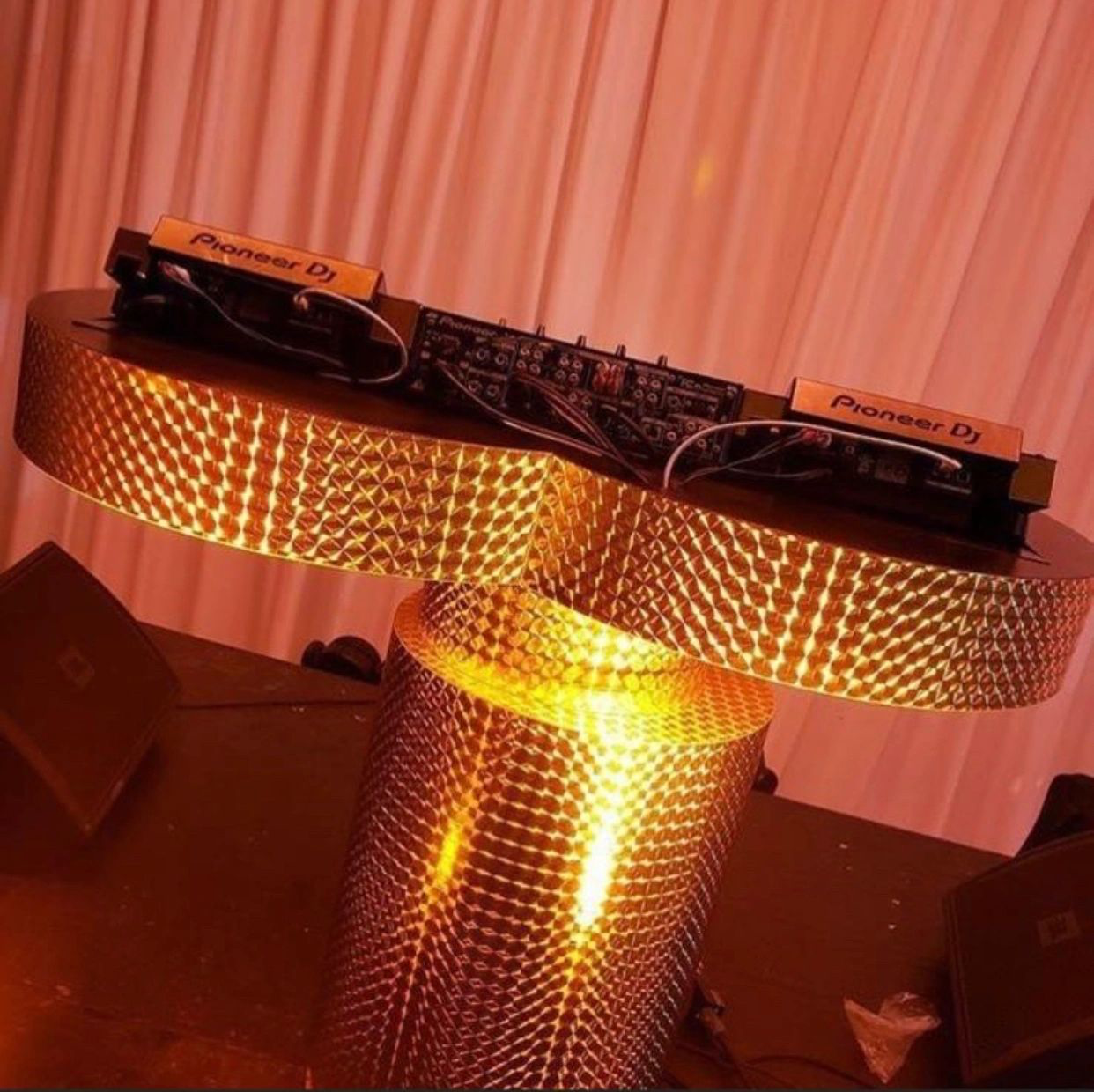 DJ setup on illuminated textured stand with Pioneer DJ equipment.