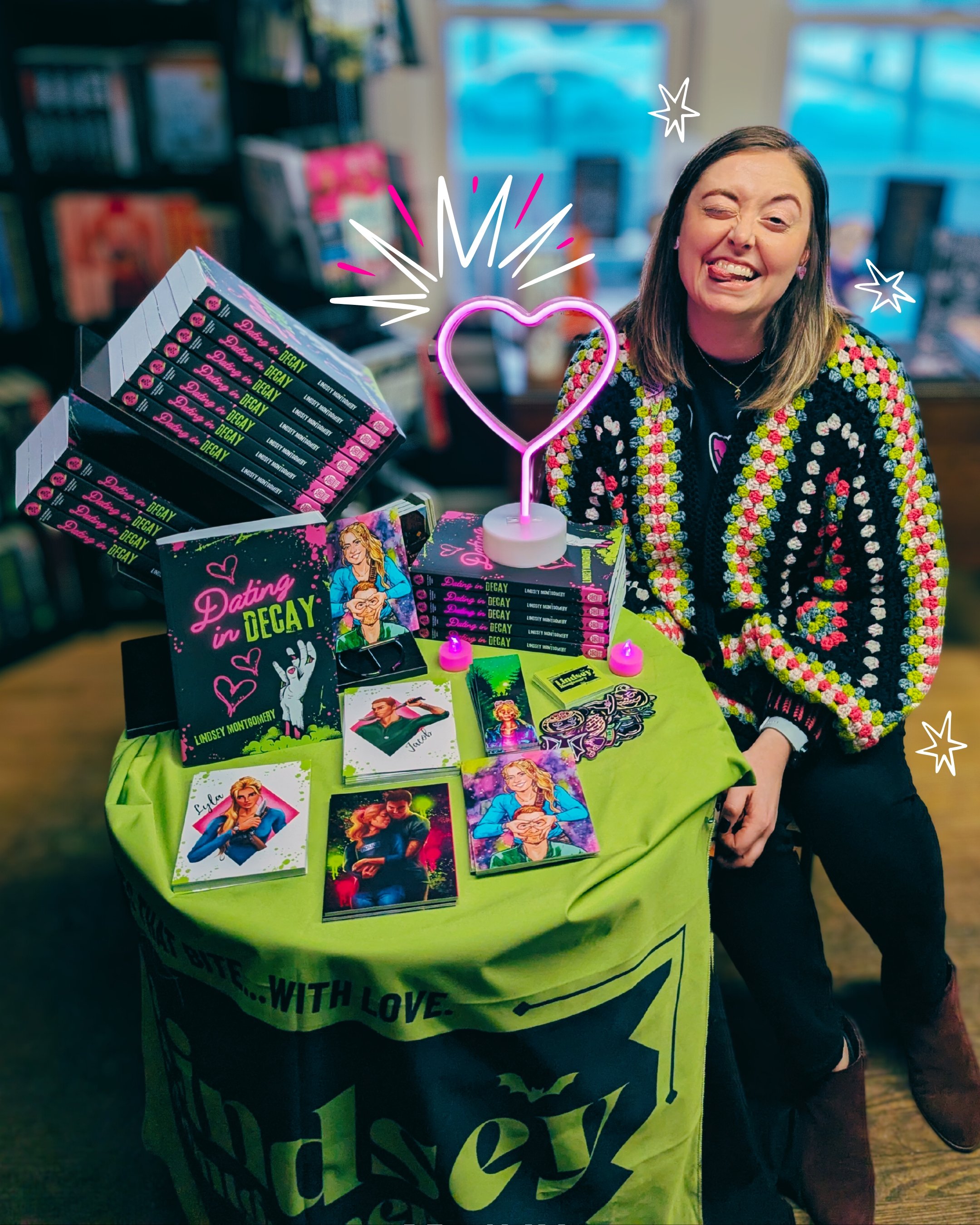 Smiling photo of author next to small display table of Dating in Decay at the Valloween event at Black Cat Books and Oddities in Medina, OH. 