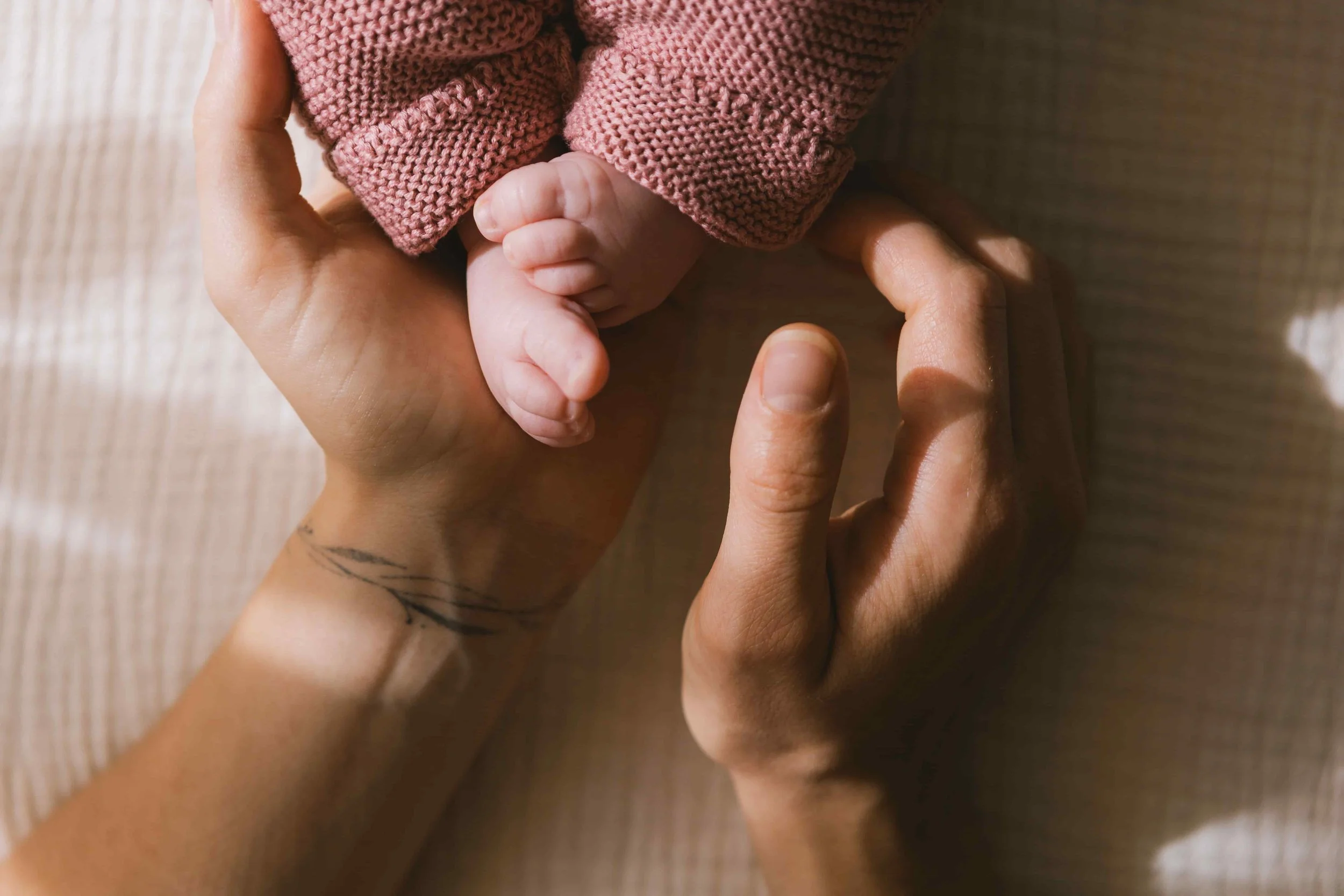 Close up of parent's hand resting on baby's feet: Could an EMDR Intensive Help with Birth Trauma?