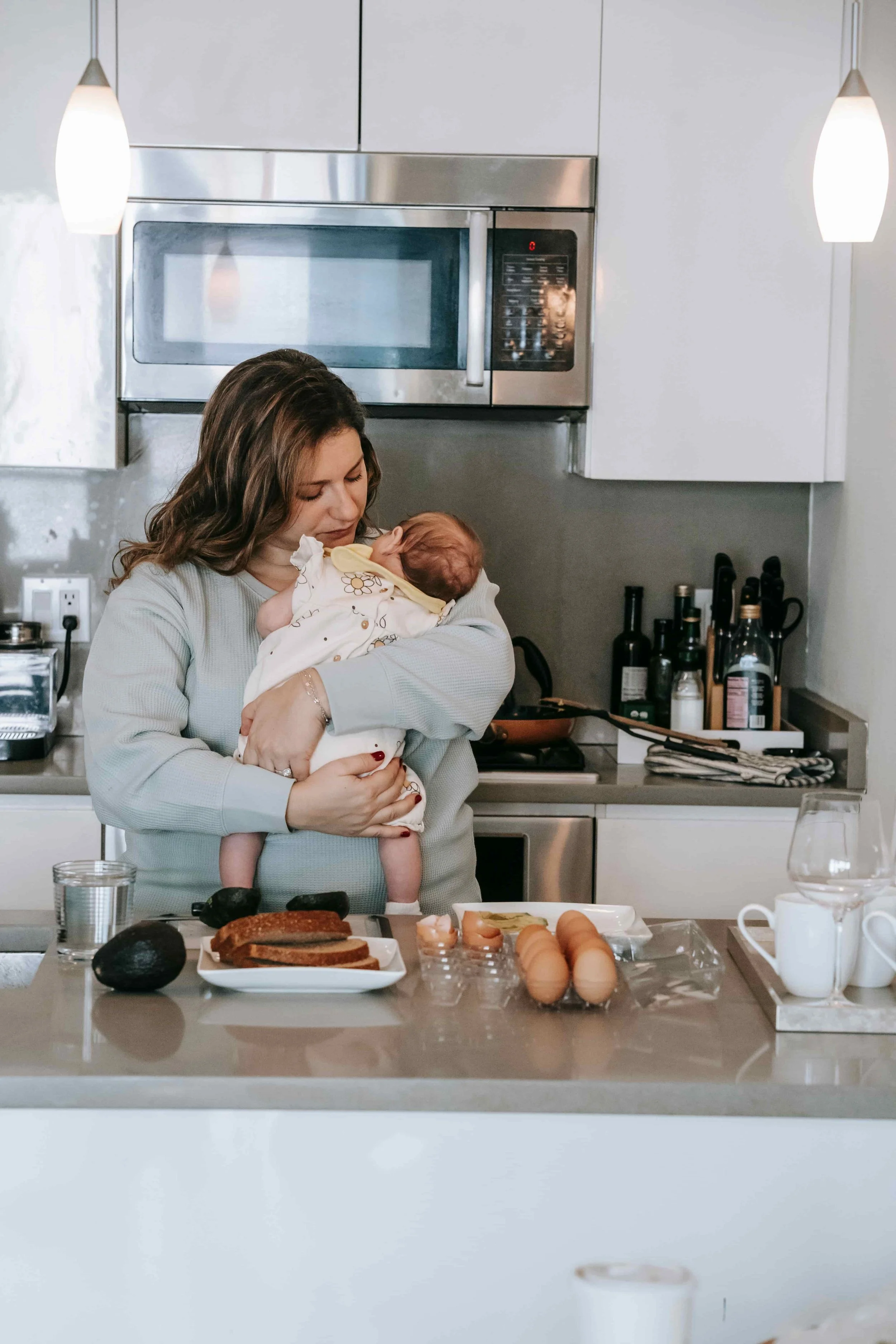 When to Seek Professional Support During Pregnancy or Early Motherhood- Mom holding newborn baby in the kitchen