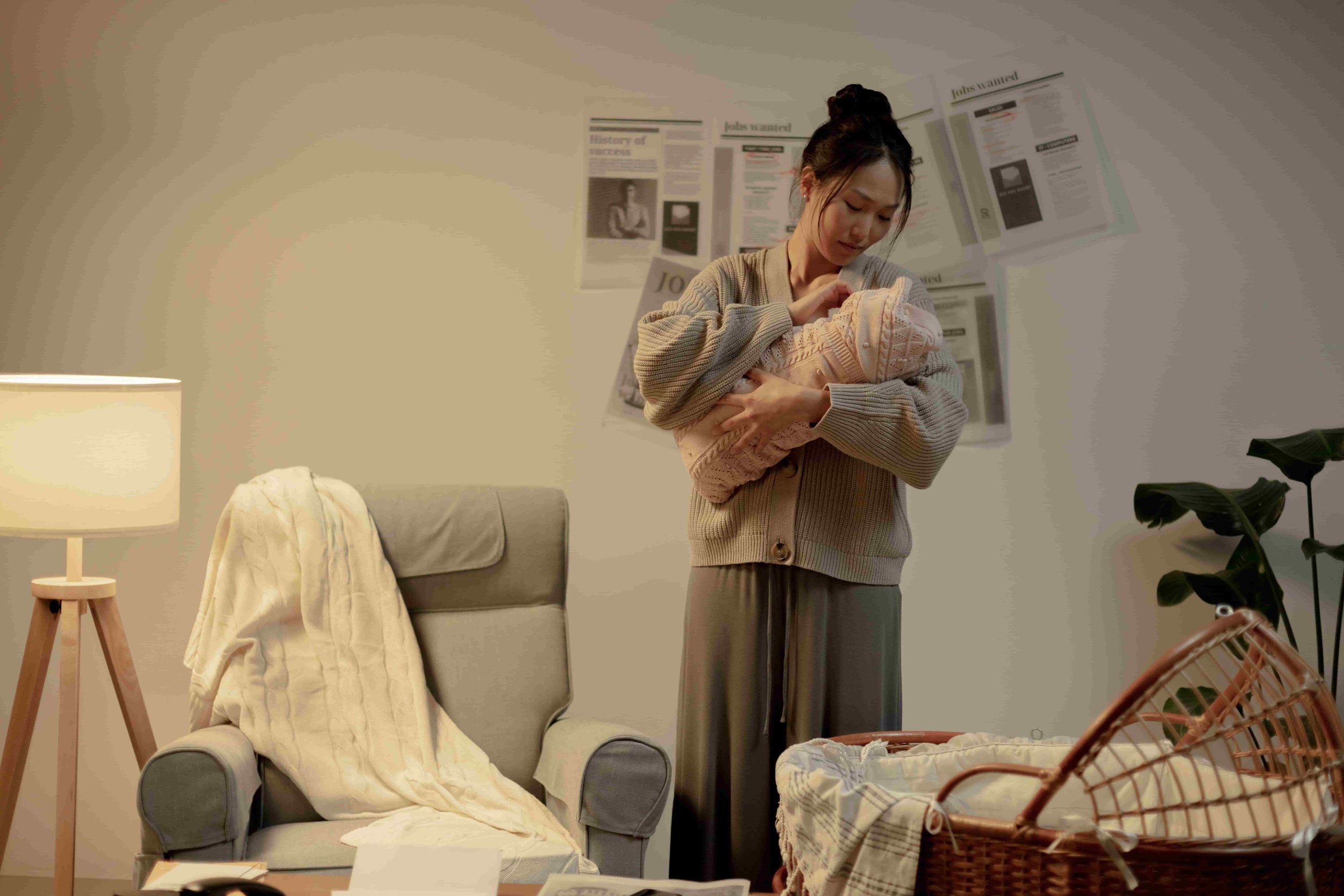 Mental Health Challenges During the Perinatal Period - Mom holding baby next to a bassinet
