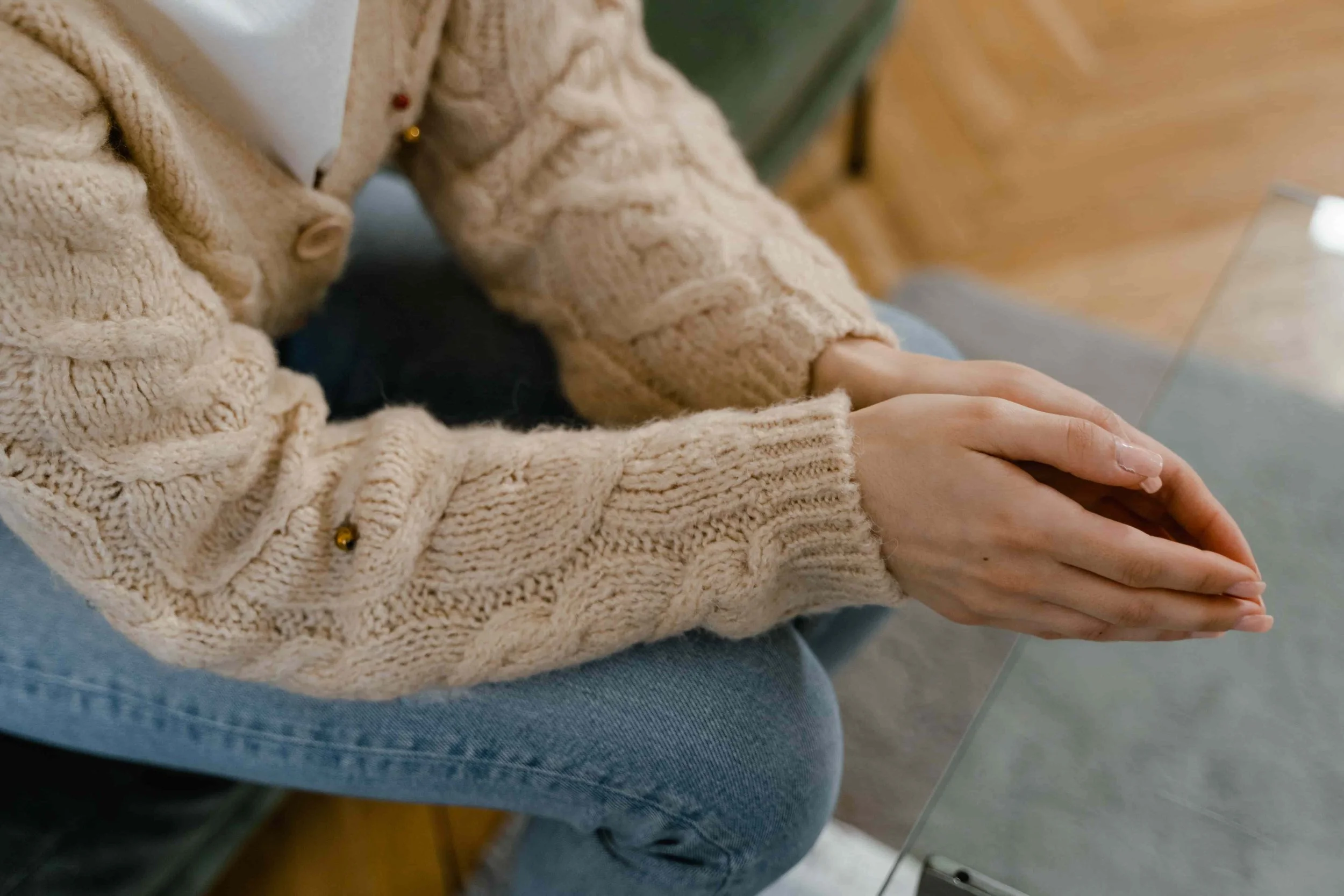 What Trauma-Informed Therapy Really Looks Like-Woman holding hands together on her lap while leaning over