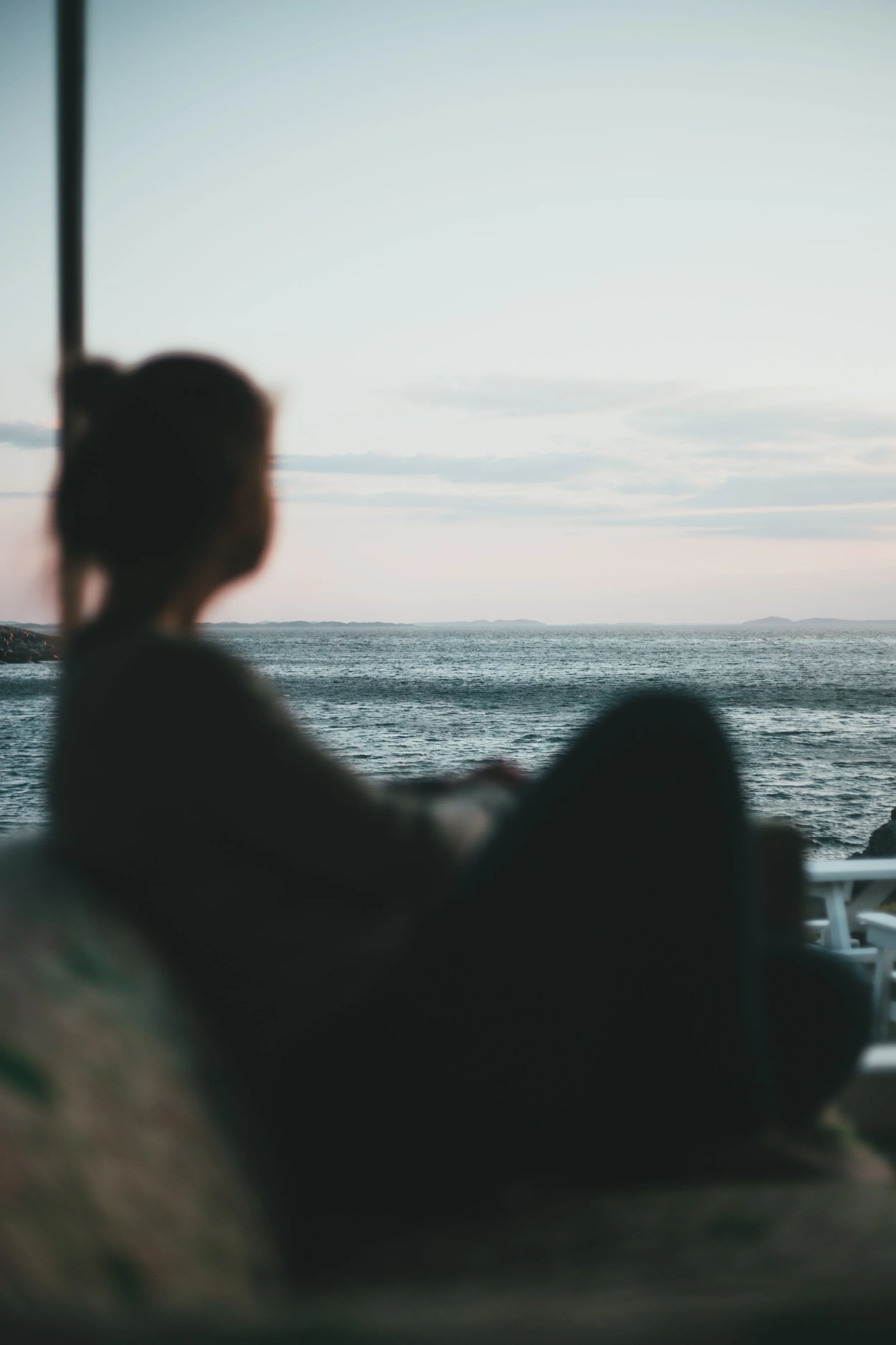 What It Means to Heal Trauma Through the Body -Image of the ocean horizon with a woman sitting by a window