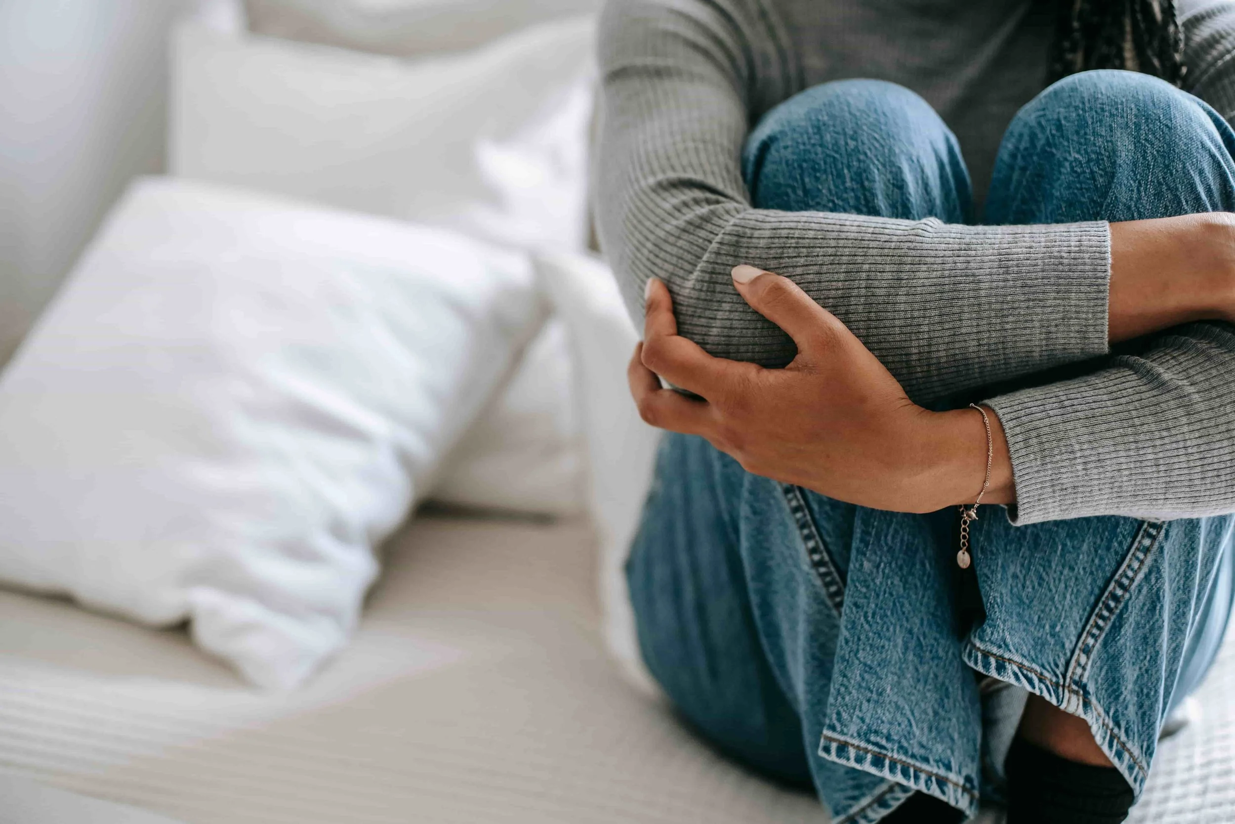 What Trauma-Informed Therapy Really Looks Like- Woman holding knees in a hug on a couch