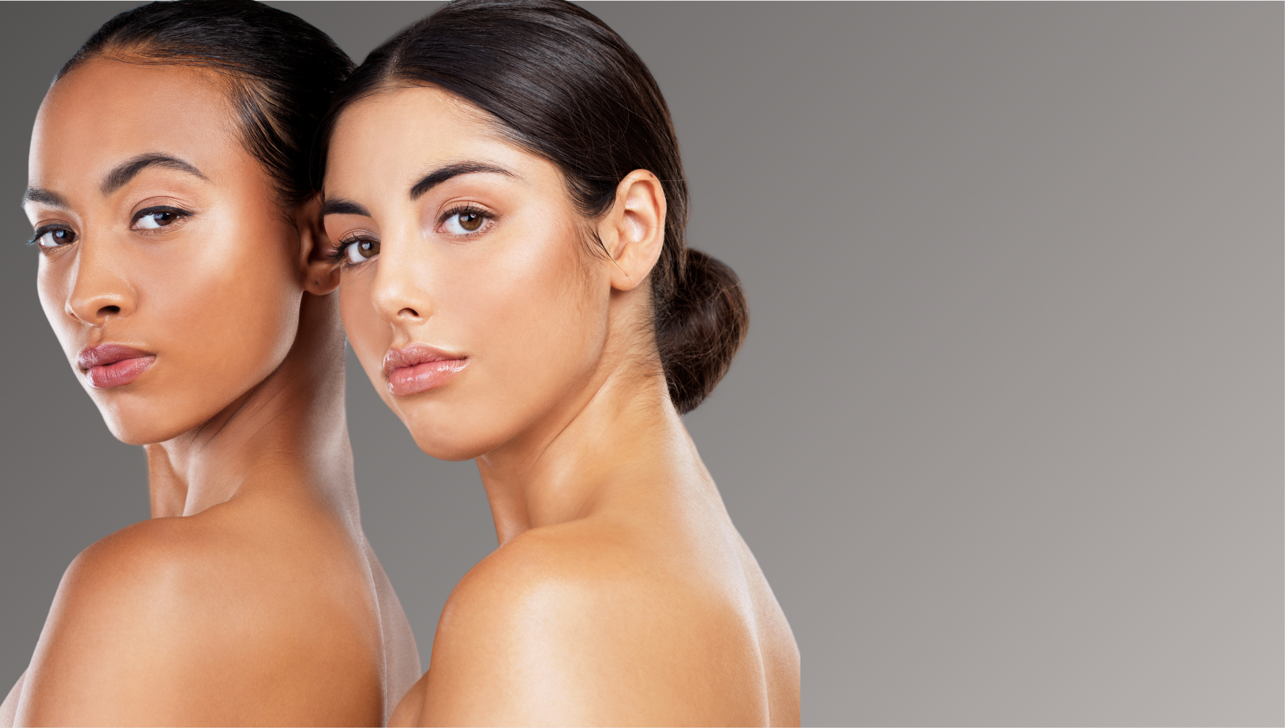 Two women with flawless skin, one with lighter skin and the other with darker skin, posing closely together against a neutral gray background.