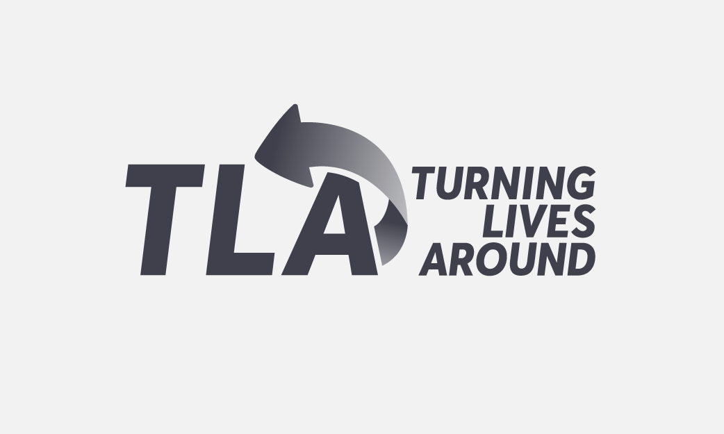 The Logo for TLA – with the letters TLA prominent and a circular arrow, accompanied by the full text 'Turning Lives Around' to the right.