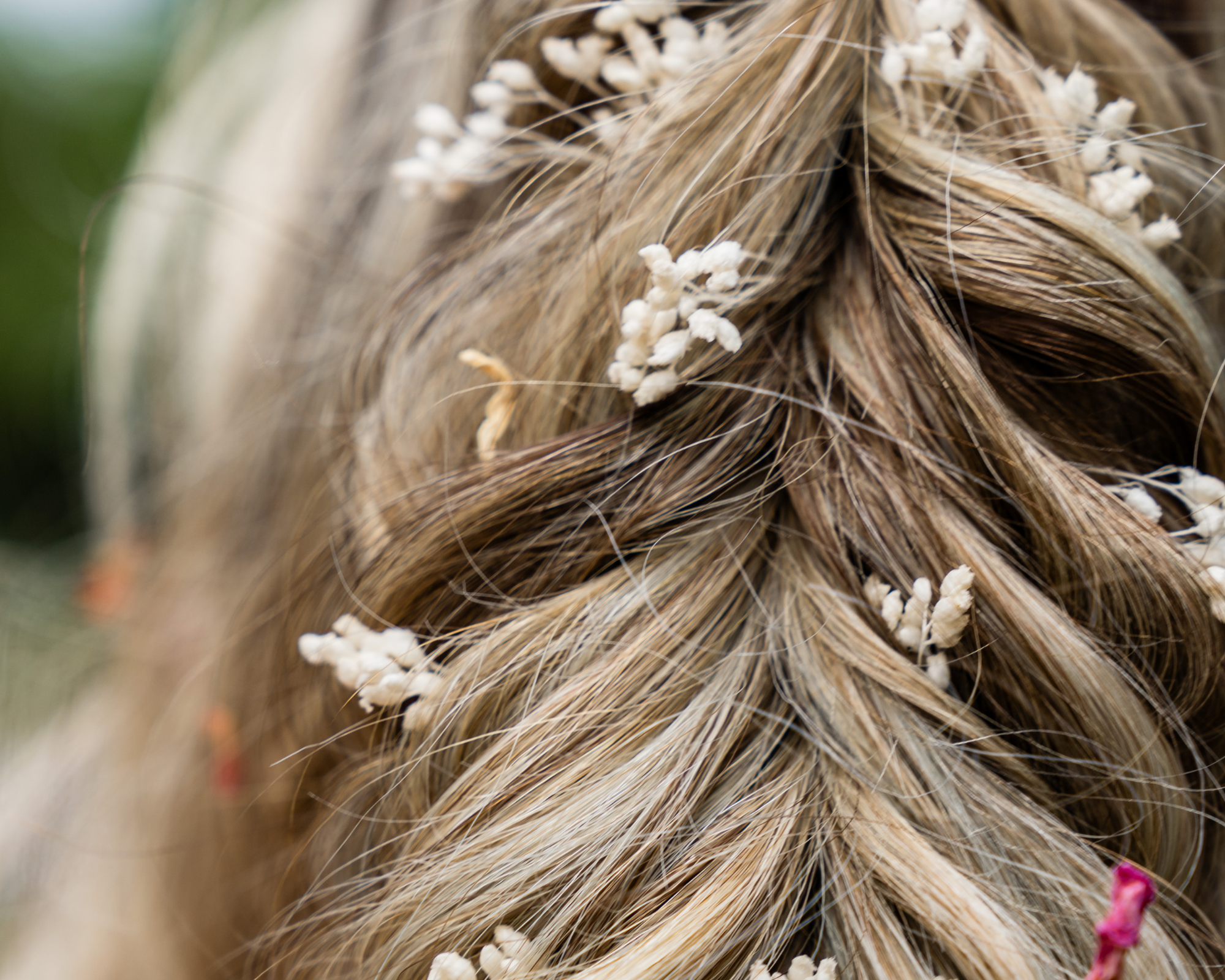 Close-up van een ingehaakte vlecht met kleine witte bloemen verwerkt in het haar.