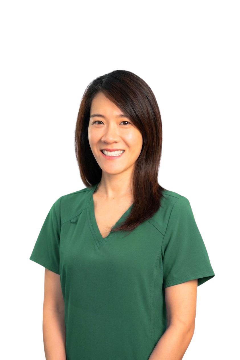 A woman with shoulder-length brown hair smiling, wearing green medical scrubs, standing against a black background.