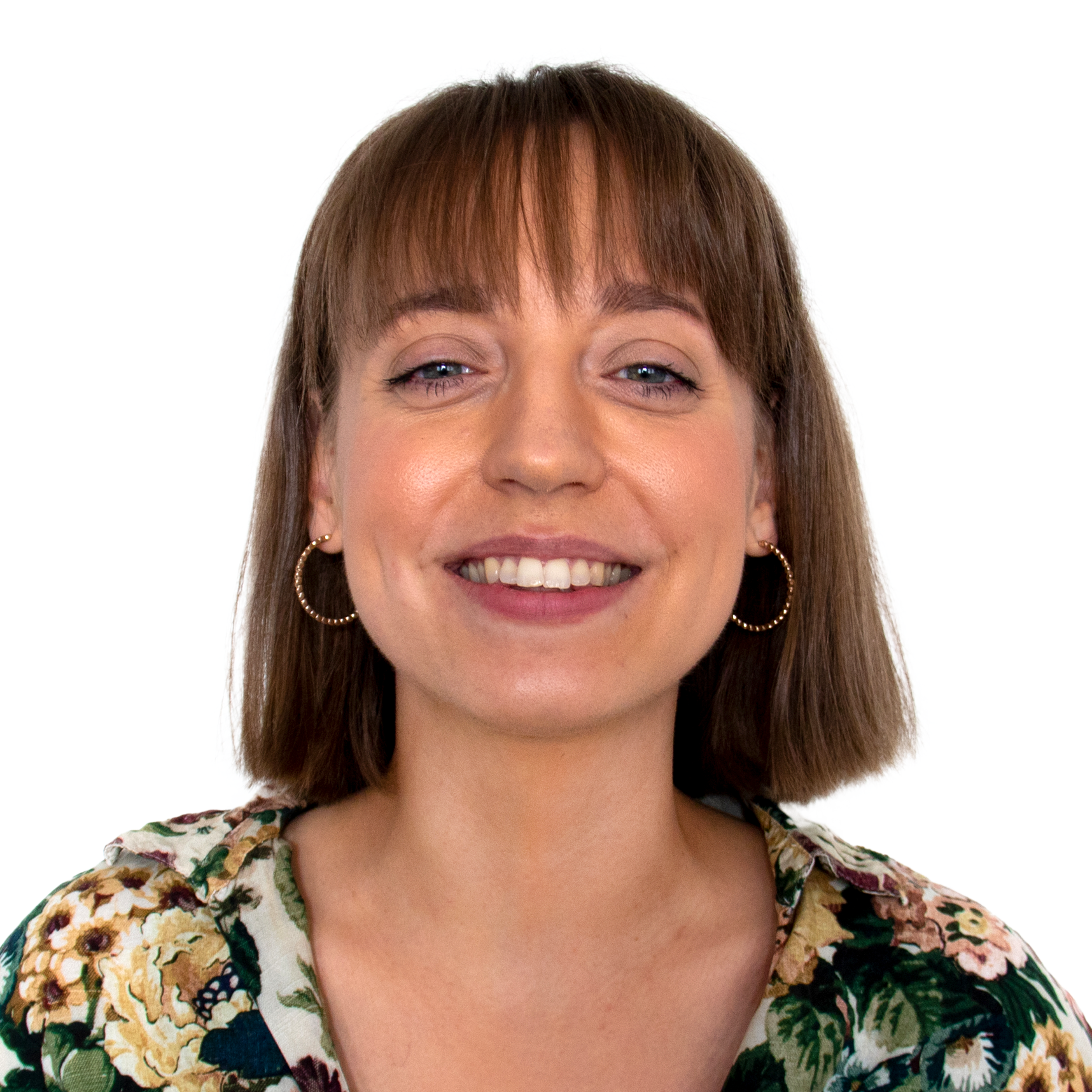 Ung kvinna med brunt hår, lockiga örhängen och blommande blus, ler mot kameran.