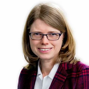 En kvinna med mellanlångt brunt hår, glasögon och vit skjorta, iklädd mörk lila och röd rutnätsjacka, ler mot kameran.