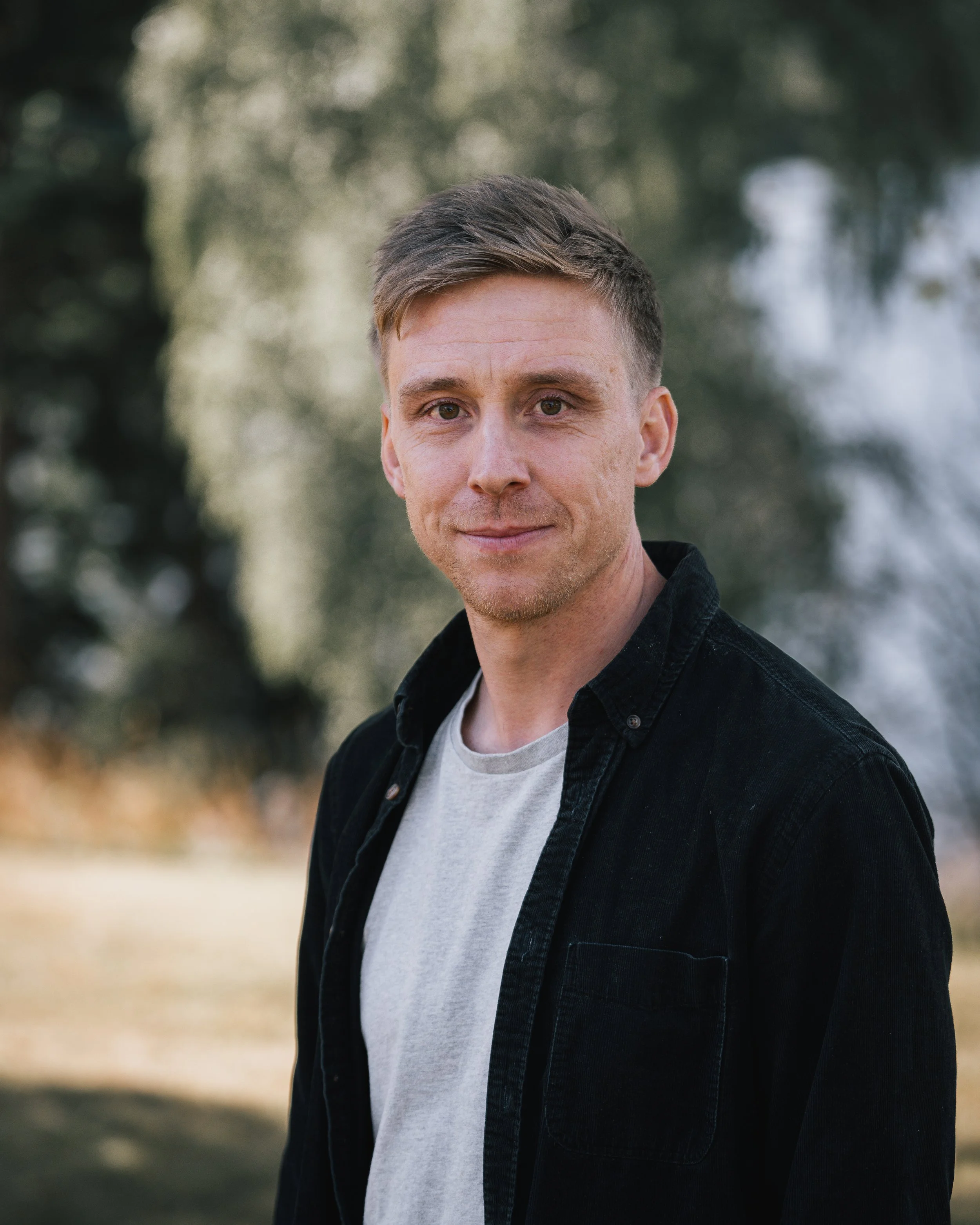 Porträtt av en man utomhus med träd i bakgrunden
