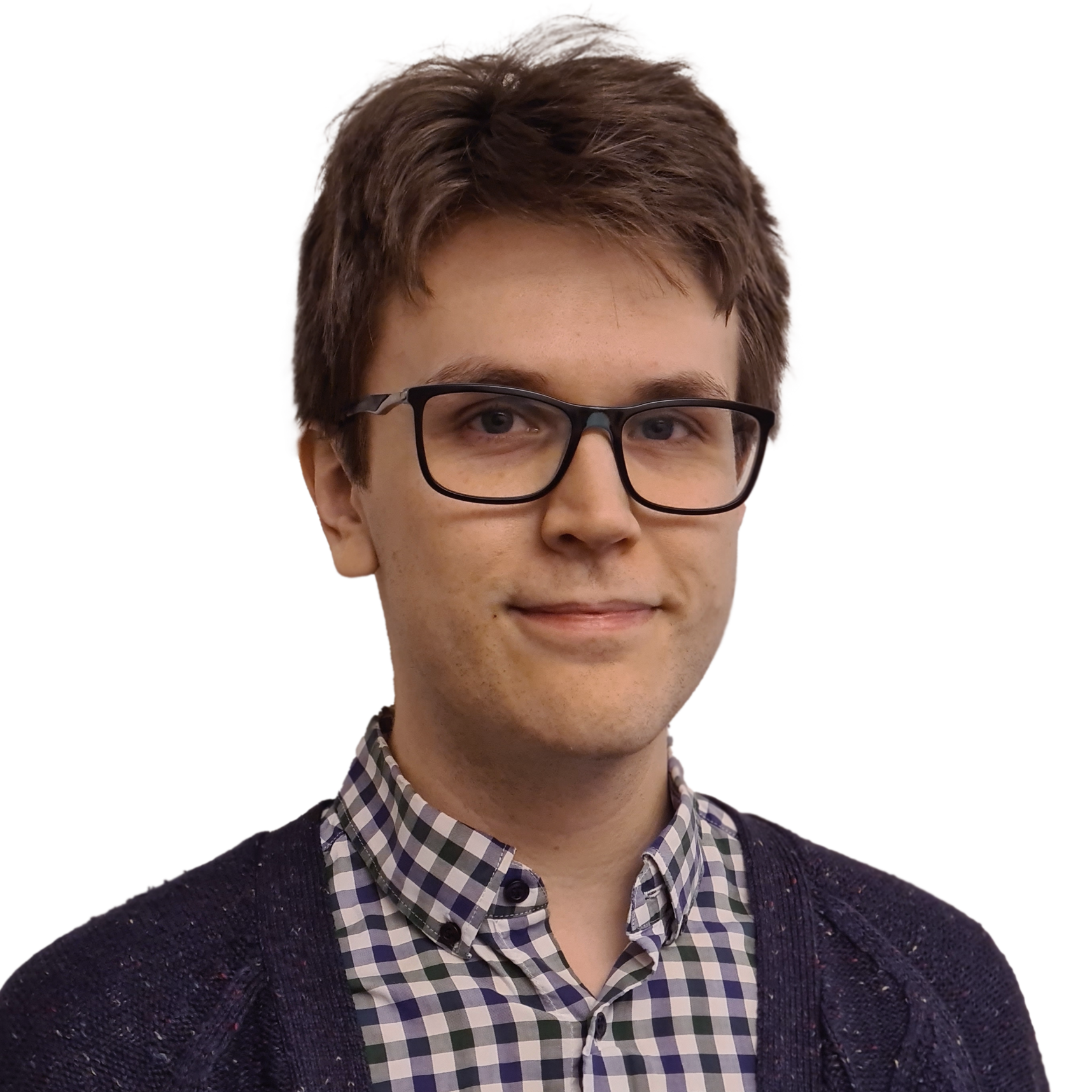 En ung man med brunt, lockigt hår, glasögon och en blick mot kameran, bär en skjorta med rutmönster och en mörk kofta.