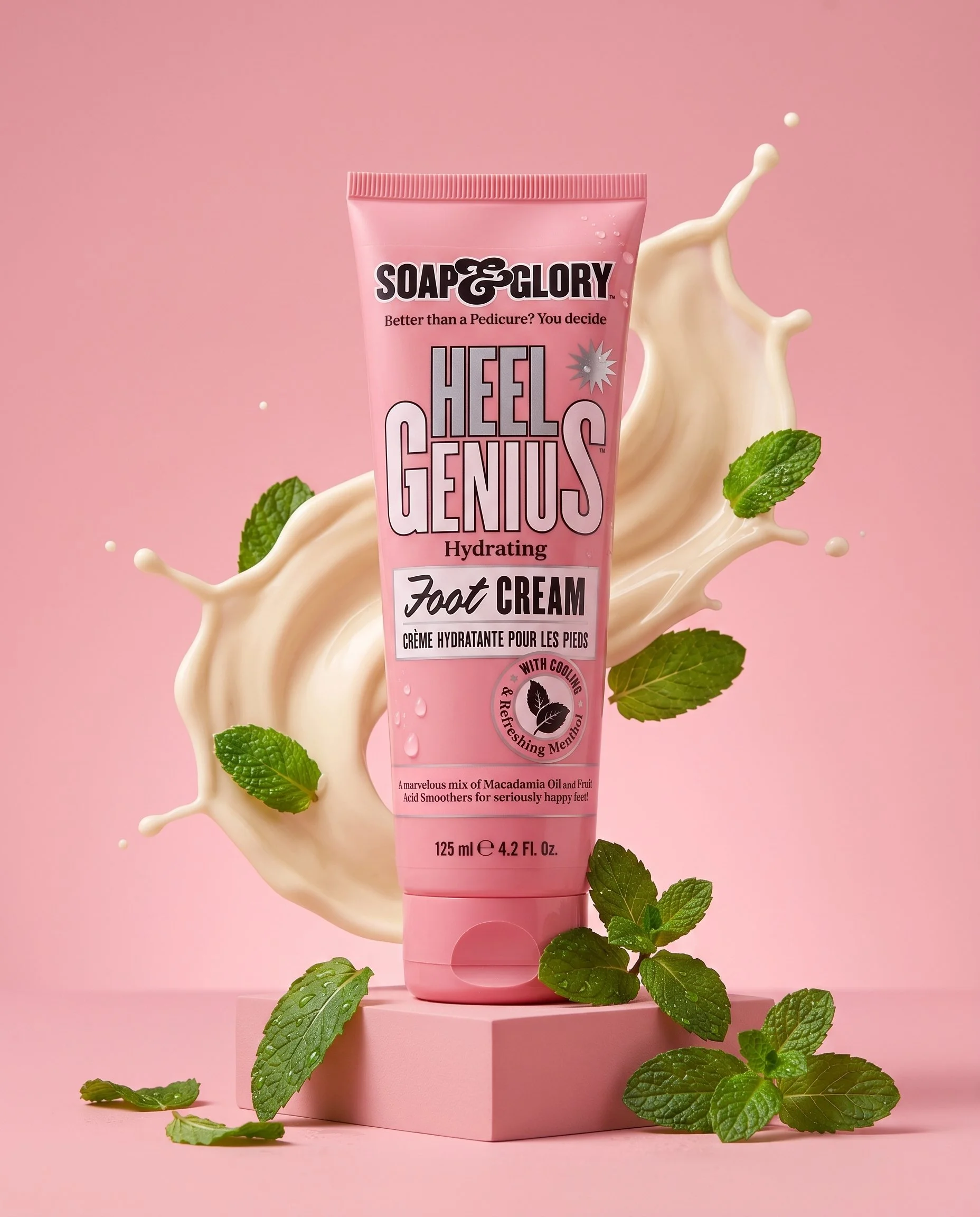 Pink tube of Soap & Glory Heel Gels foot cream with splash of cream and green mint leaves against pink background.