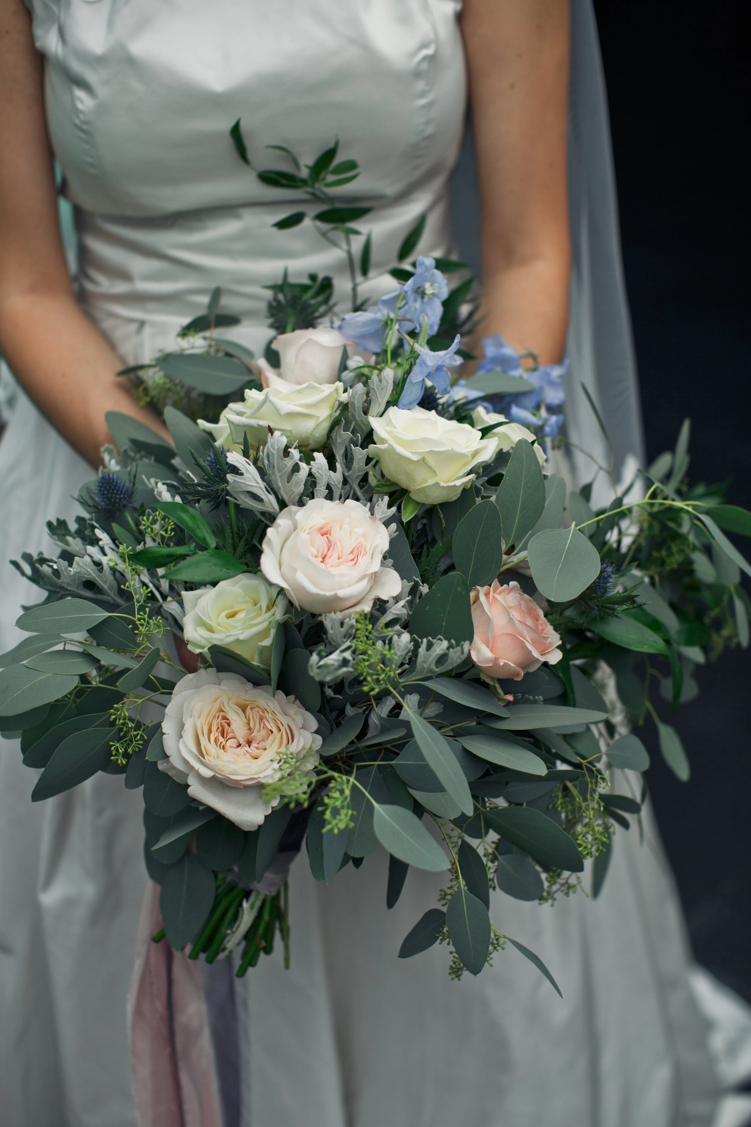 bride-holds-large-wedding-bouquet-made-greenery-white-roses.jpg