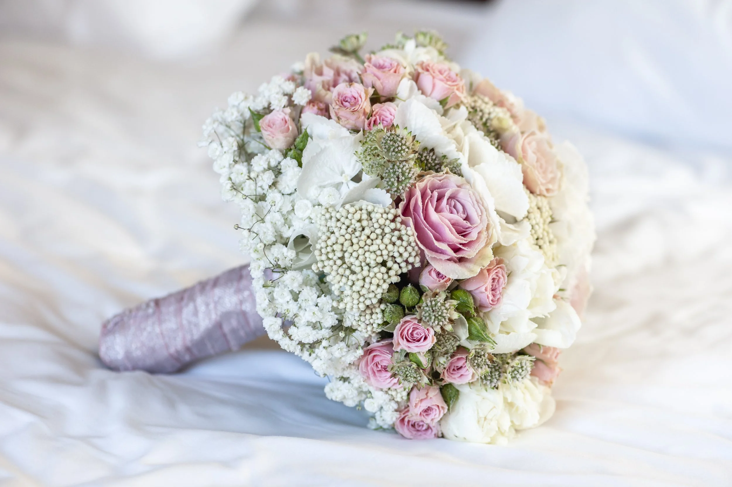 closeup-shot-bridal-bouquet-white-sheet-with-white-pink-green-colors.jpg