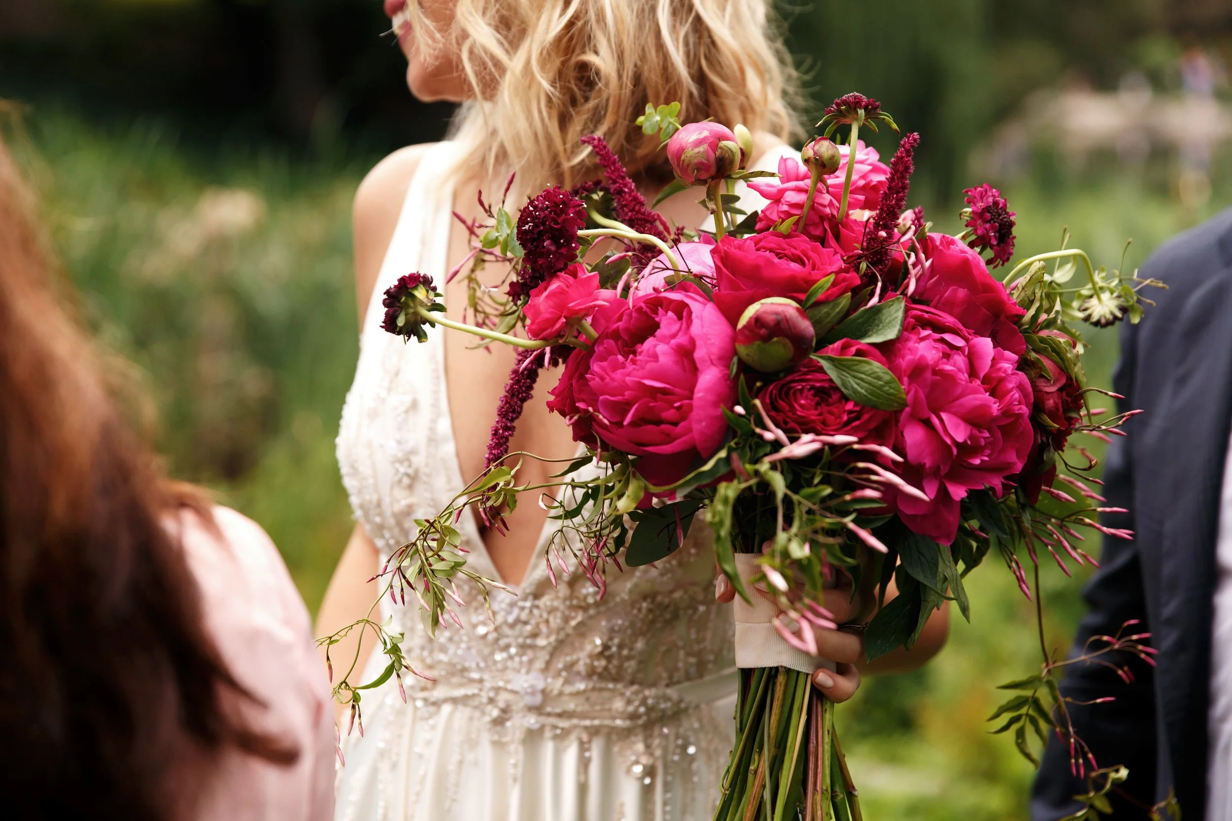 pretty-bride-holds-rich-dark-pink-bouquet-peonies-her-arm.jpg