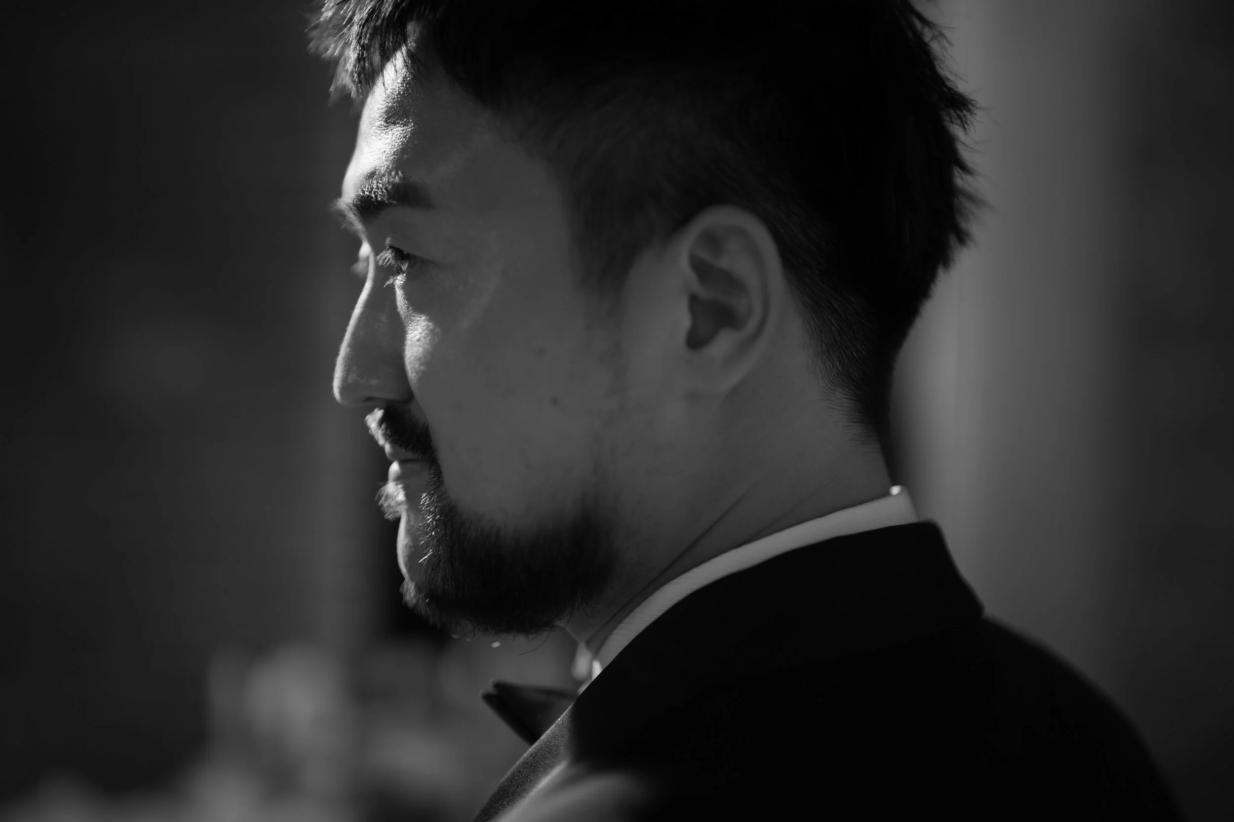 Black and white photo of a man in profile, dressed in formal attire, with a slight smile, looking to the left.