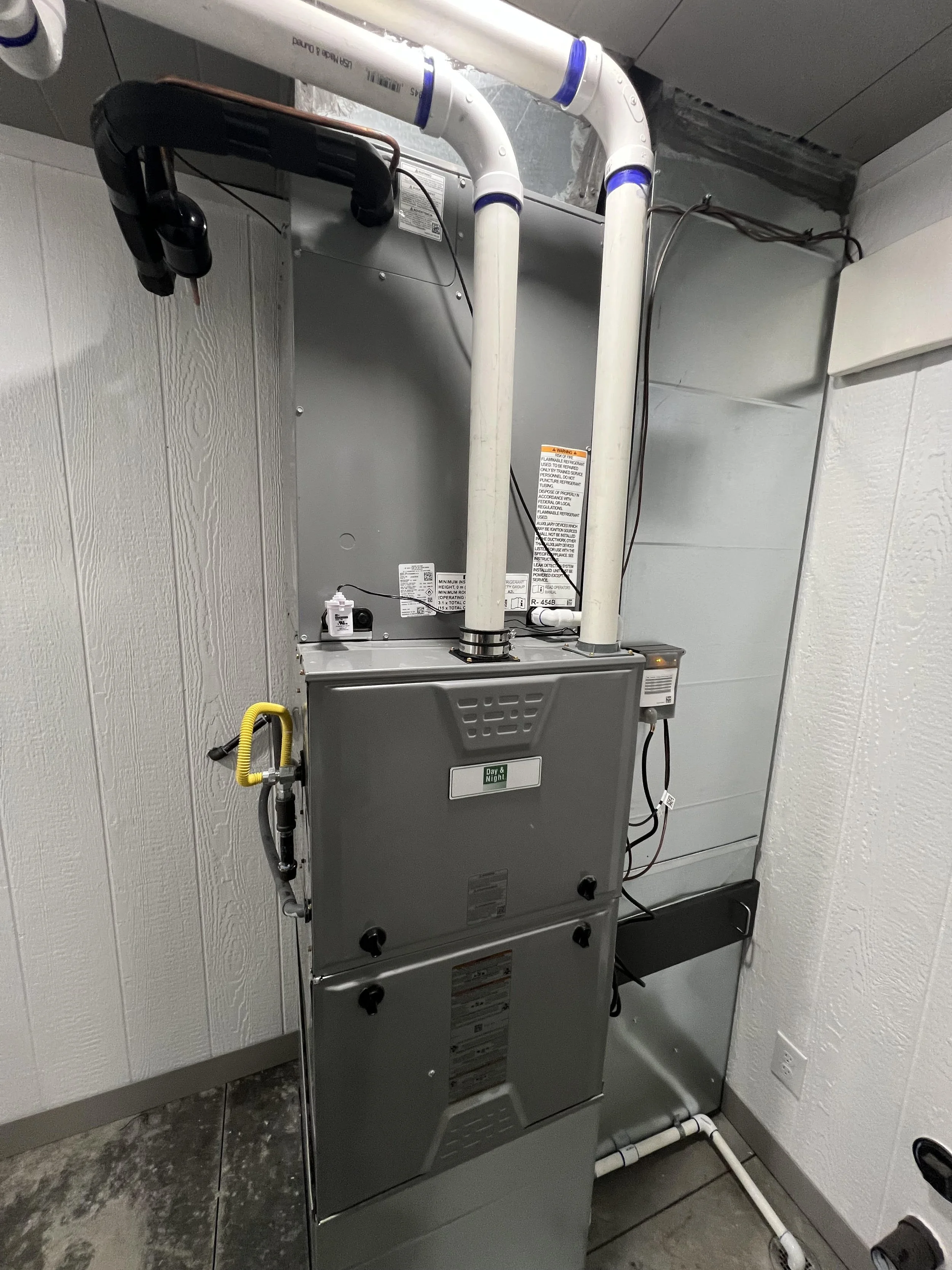 An HVAC unit with ductwork and piping in a utility room.