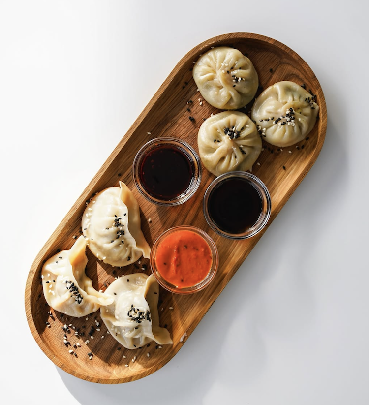 Bio-Rind und Vegi Momos von Momofaktur.ch auf einem Holztablett serviert.