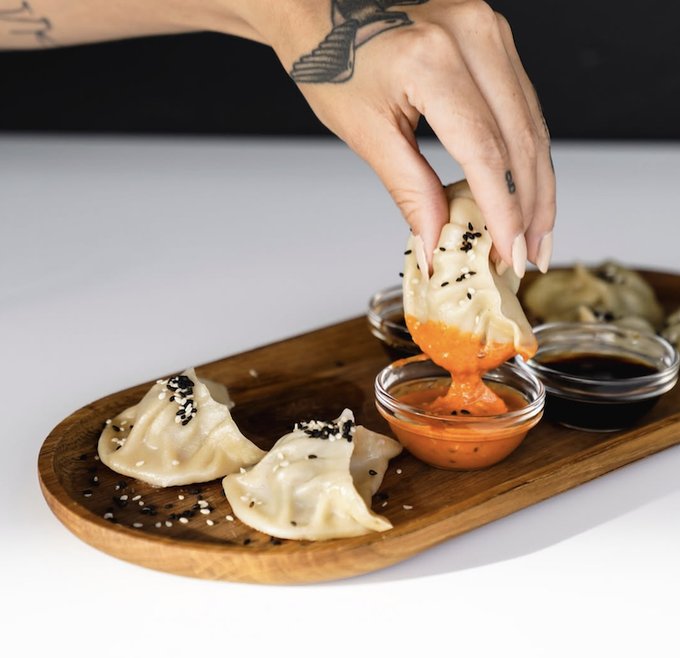 Bio-Rind und Vegi Momos von Momofaktur.ch auf einem Holztablett serviert.