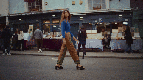 A woman walking across a street market with market stalls in the background.