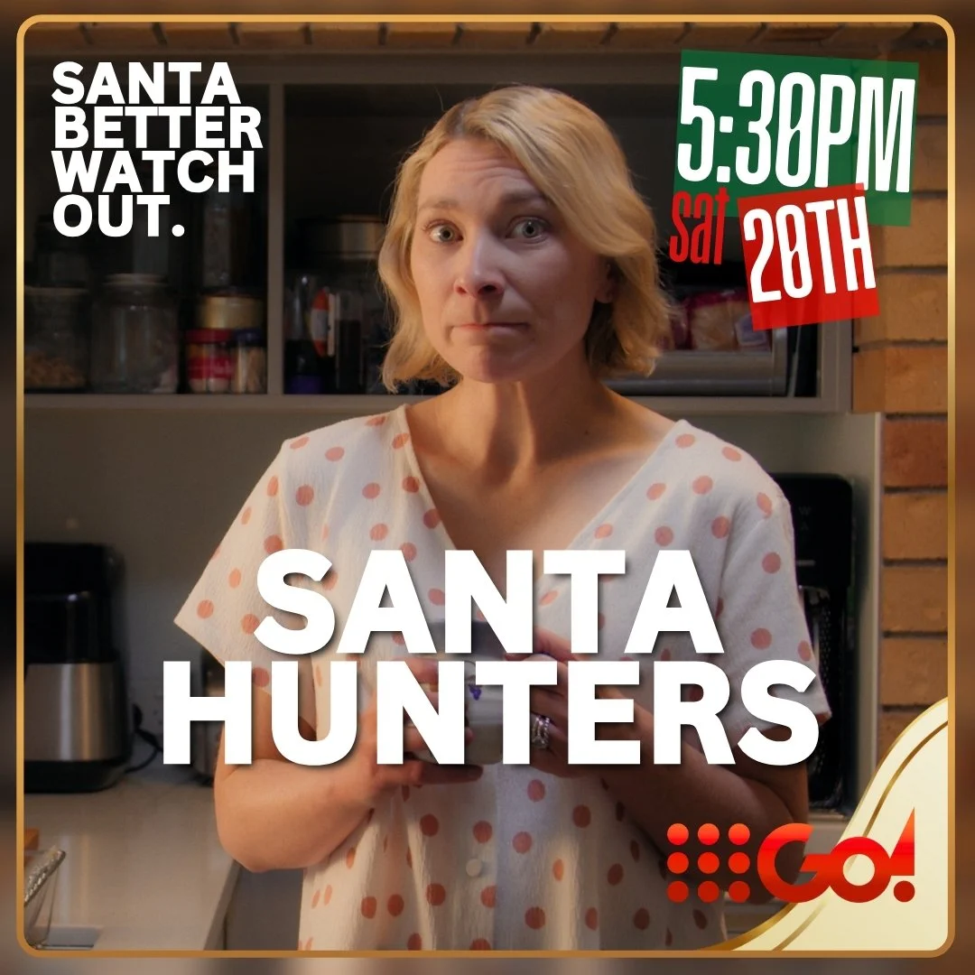 A woman with blonde hair in a polka dot shirt holding a phone in a kitchen, with text overlay about a TV show called 'Santa Hunters' airing on 9Go at 5:30 PM on Saturday the 28th.