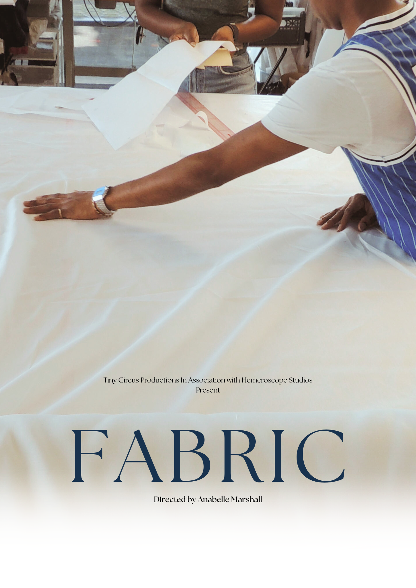 A person measuring fabric with a ruler on a worktable in a sewing or design studio.